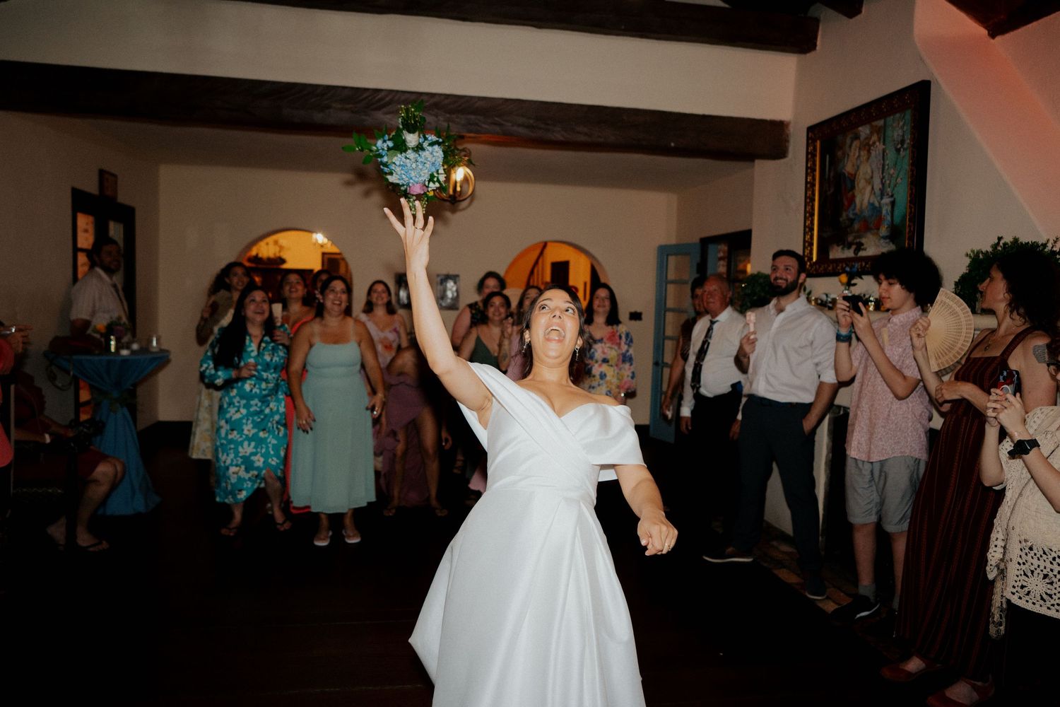 Wedding reception dance party with guests celebrating on a crowded dance floor under warm lighting.