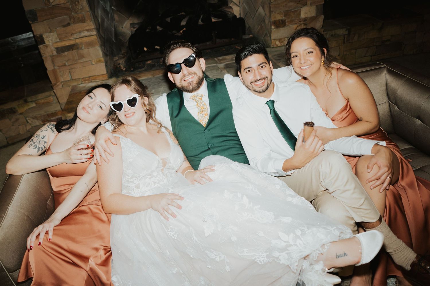 Bride and groom with wedding guests posing together on a couch wearing fun sunglasses at wedding reception at Club Lake in Apopka