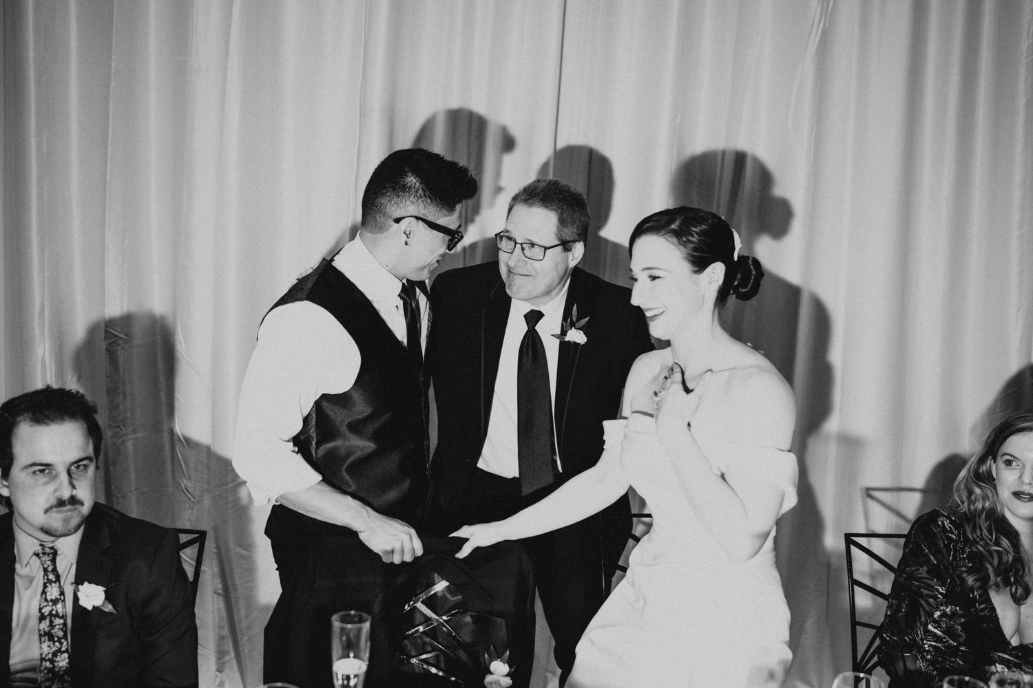 Black and white photo of wedding reception guests mingling and dancing.