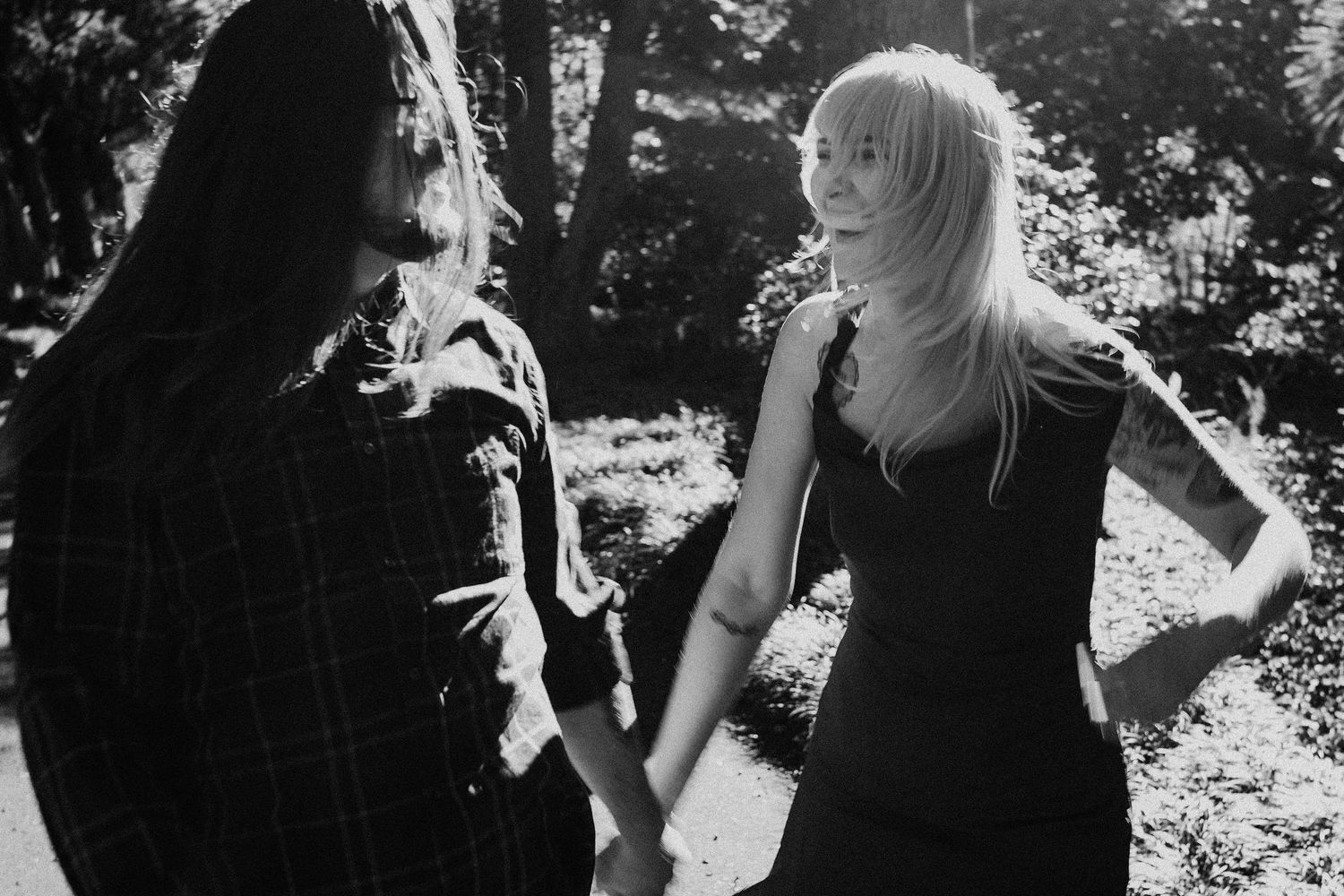 A black and white photo showing two people sharing a playful moment in nature.