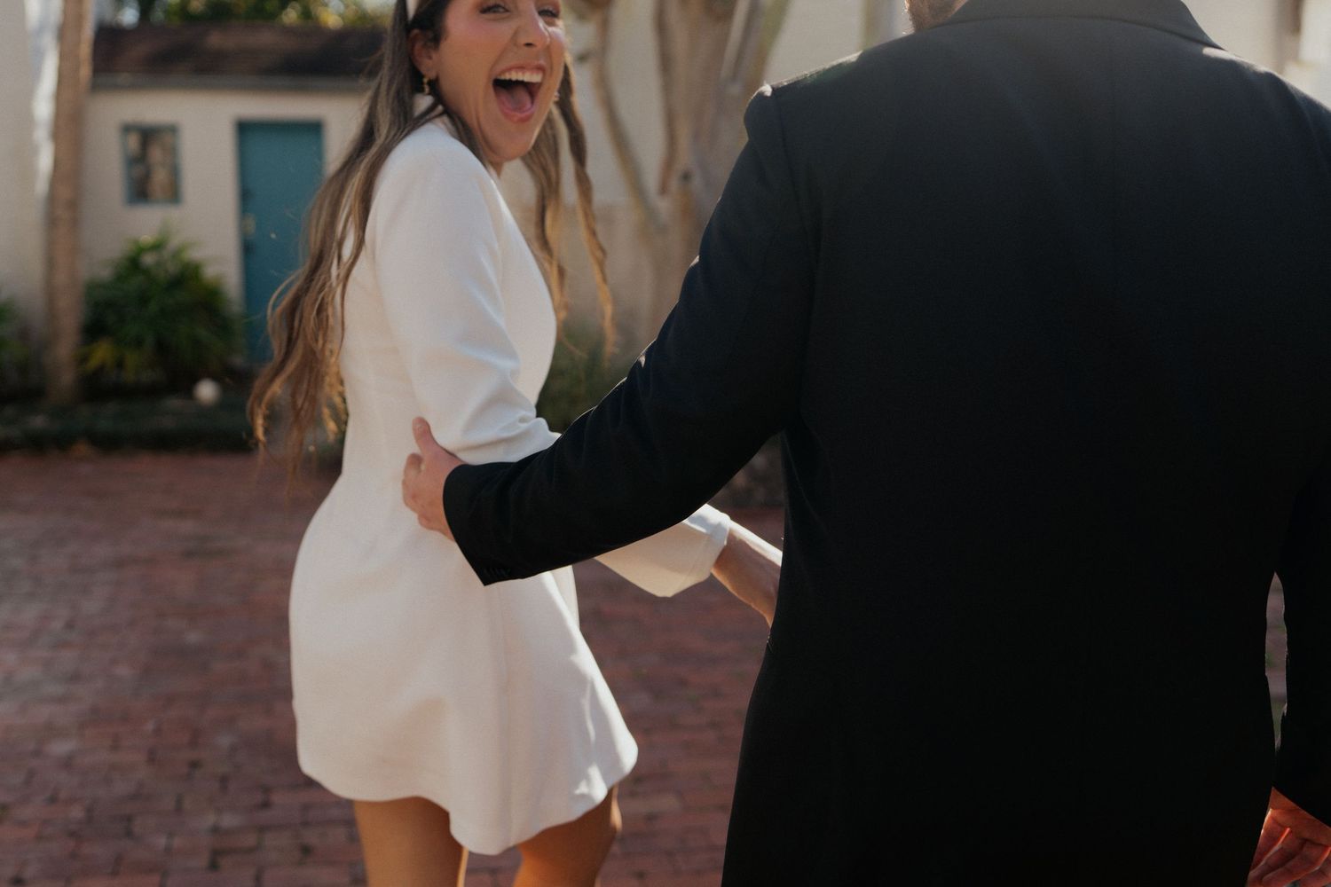 A couple shares a joyful moment together during a wedding photo session on a brick pathway.