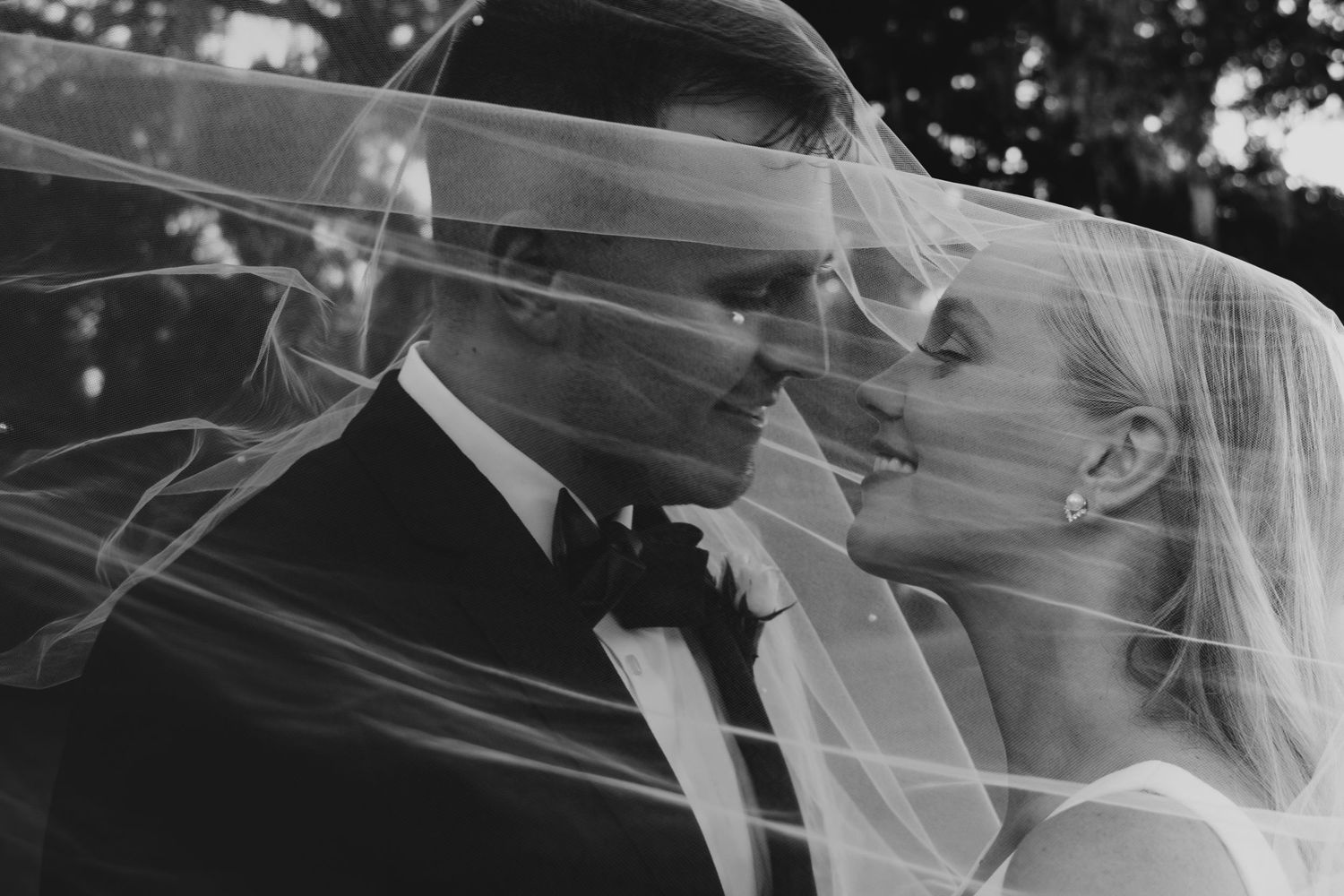 Black and white wedding photo of bride and groom sharing intimate moment under flowing veil in new york.