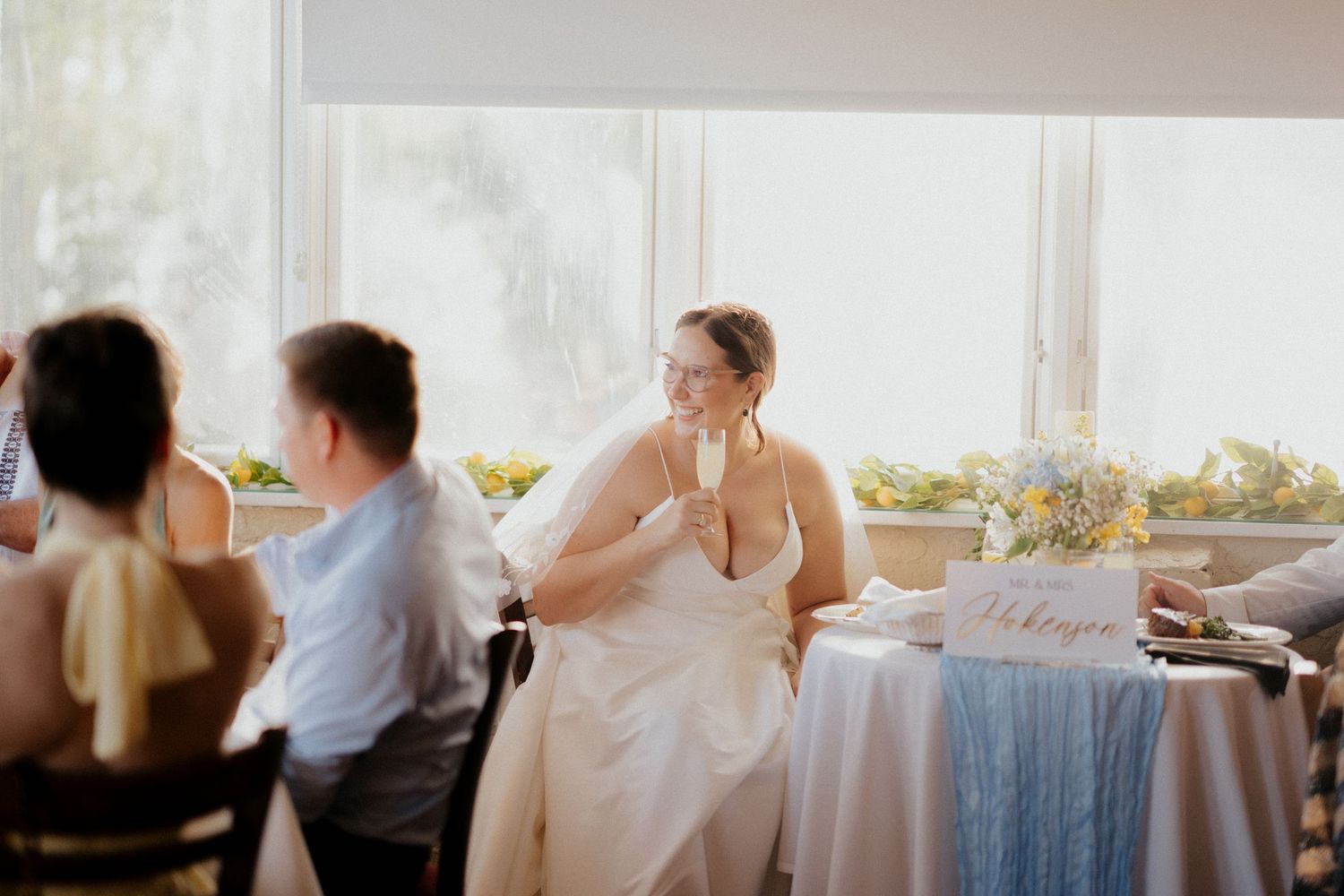 Elegant wedding table with blue runner and bride at a bright sunlit reception venue.