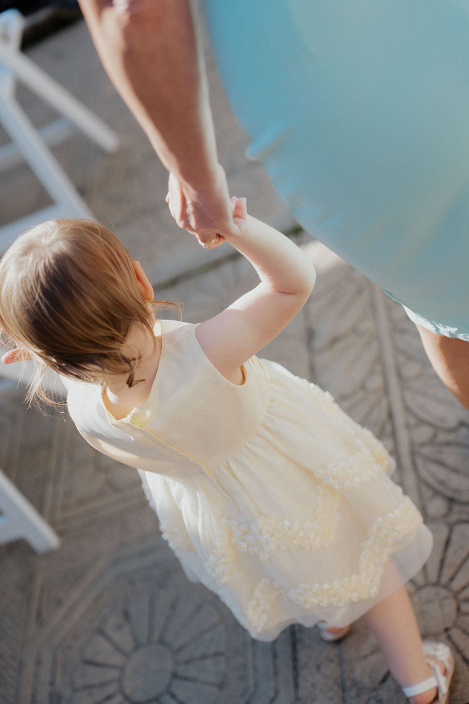 A small child in a white lace dress twirls and dances in a series of motion shots.