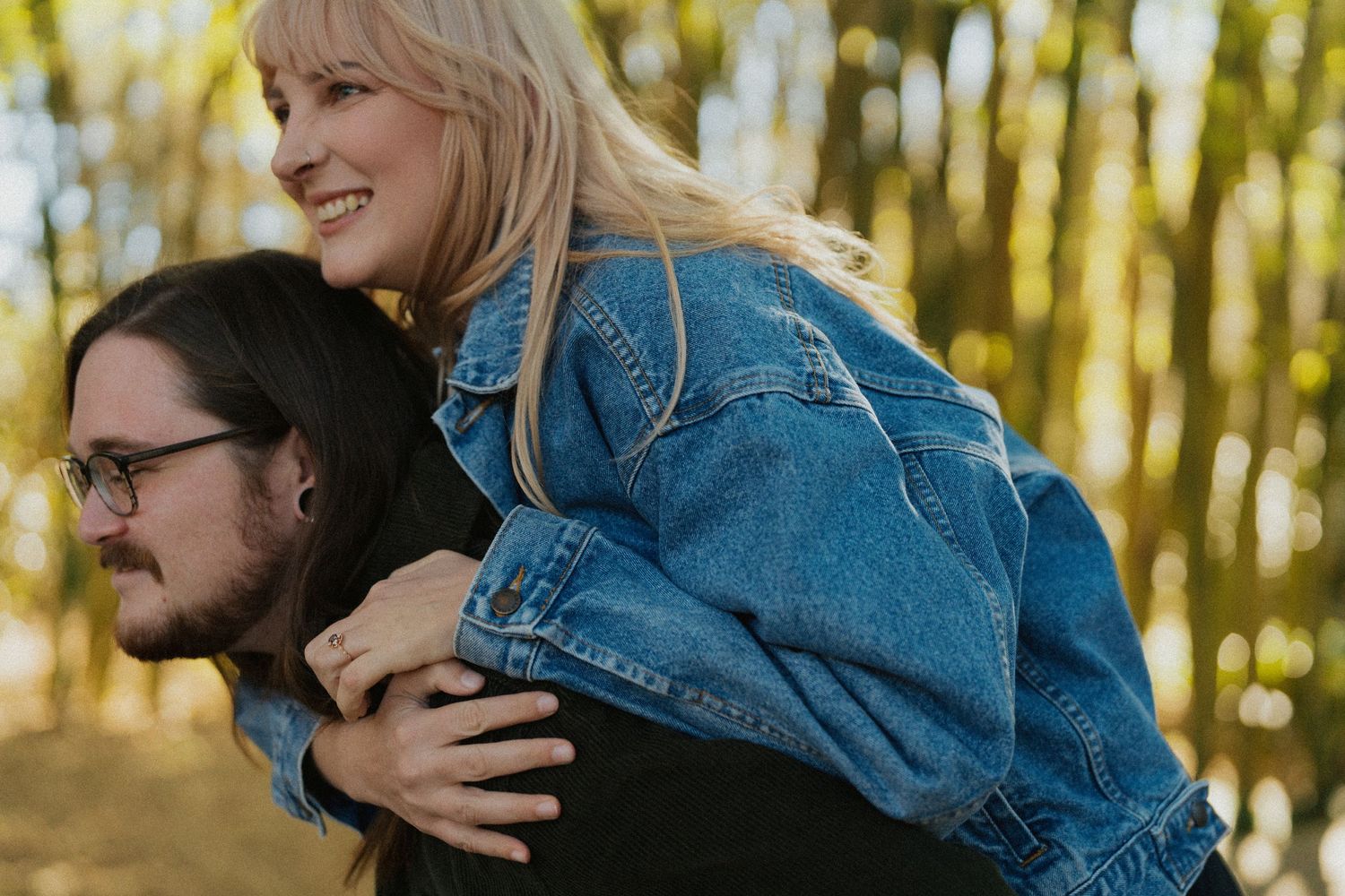 A playful piggyback moment captured in warm sunlight against autumn foliage.