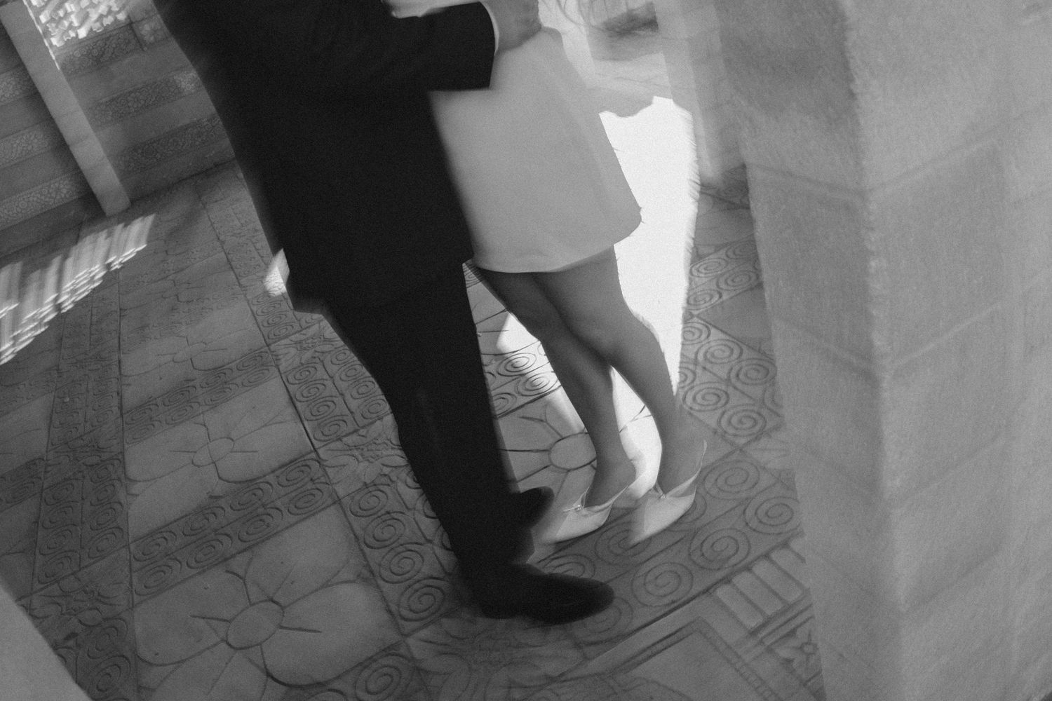 Black and white photograph showing people in formal attire walking together in an indoor setting.