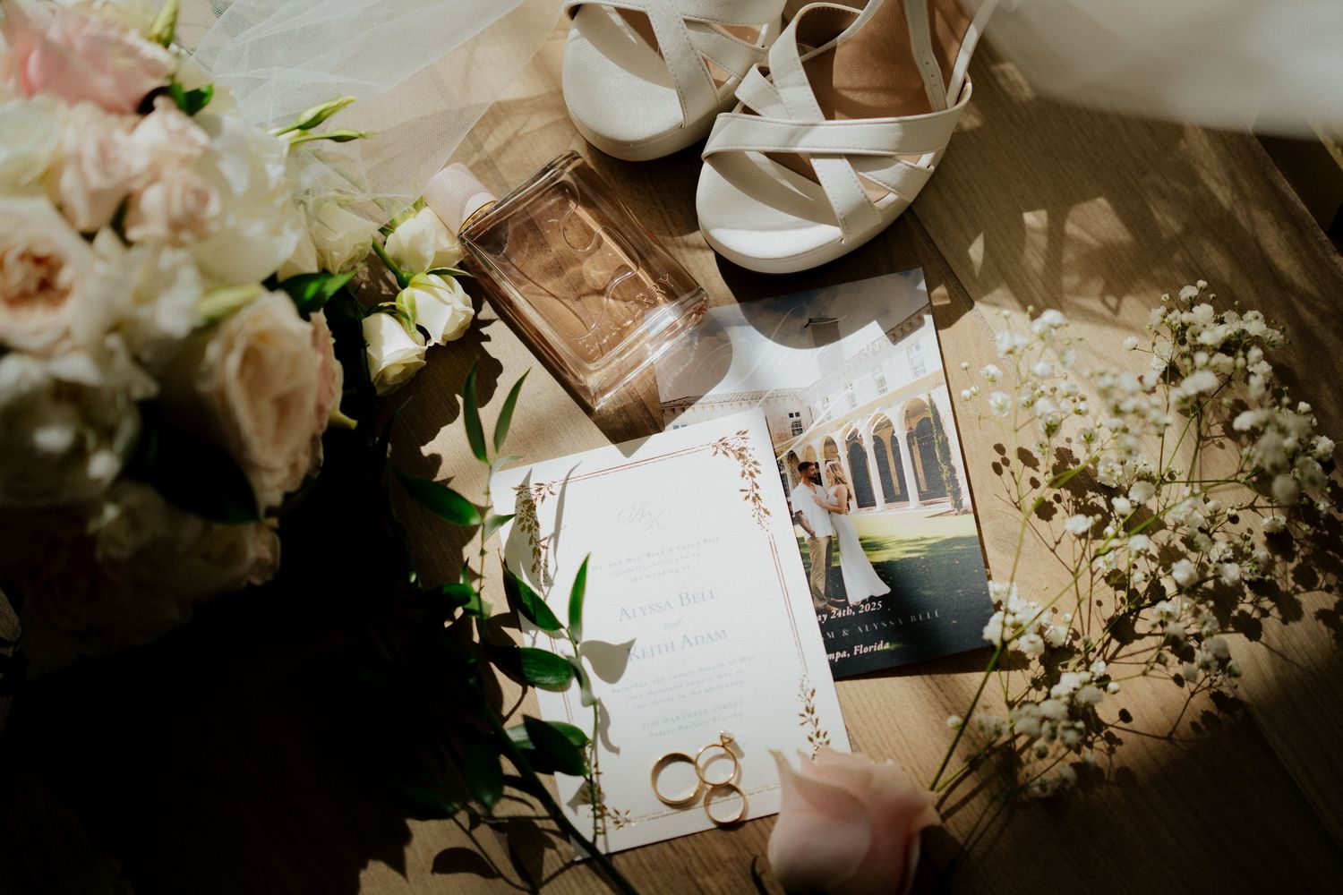 Flat lay of wedding details including rings, invitation, bridal shoes, and floral bouquet.