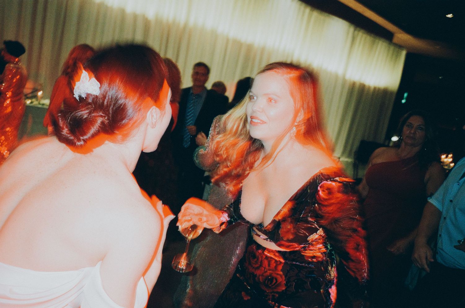 People dancing and having fun at a dimly lit party with red lighting effects.