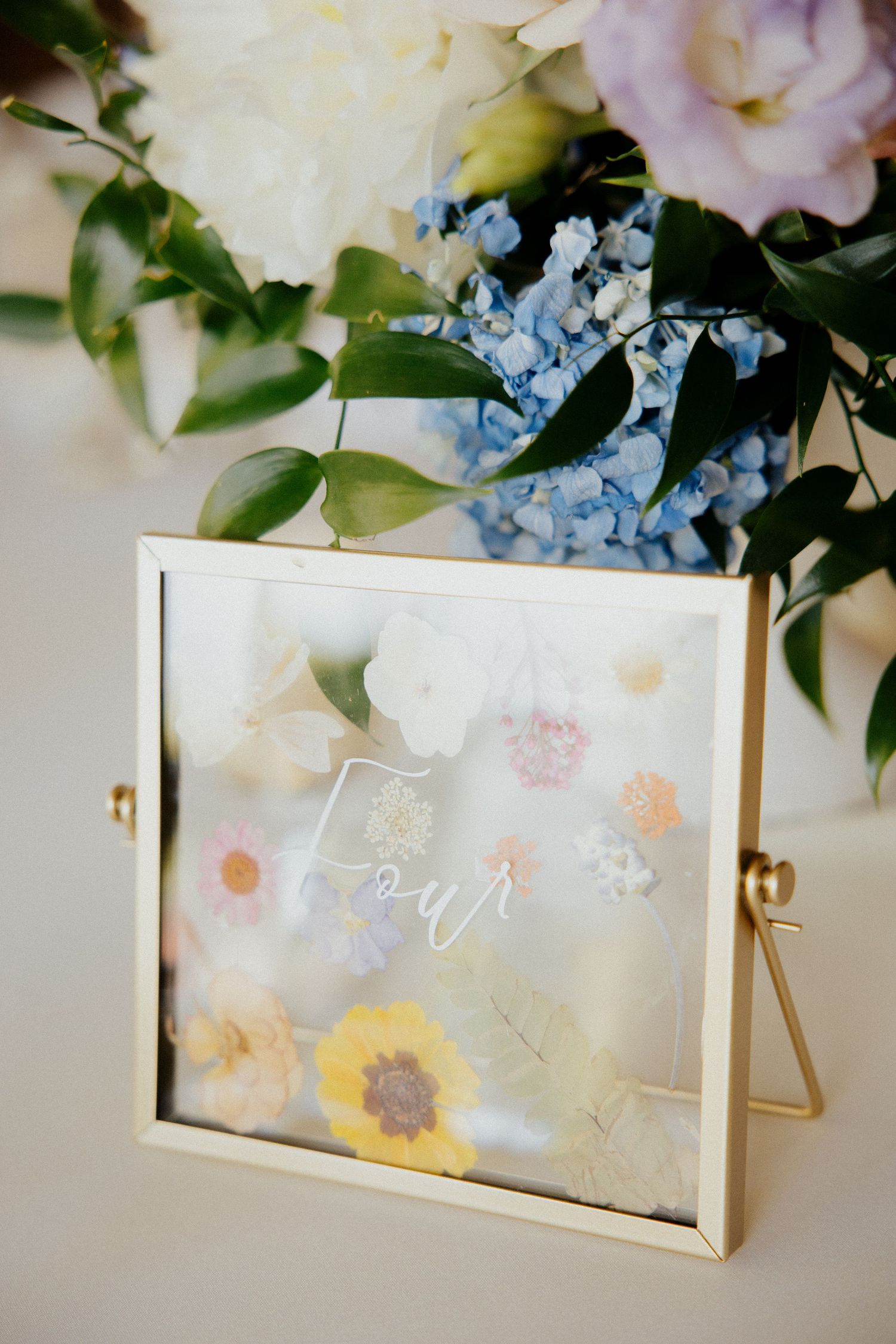 Clear acrylic wedding signage decorated with delicate blue and white flowers.