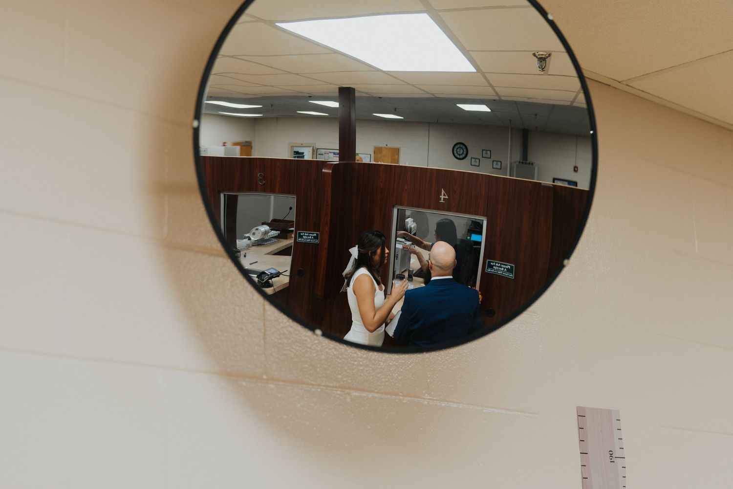 A mirror reflection shows a couple seated in what appears to be an office or courthouse interior.