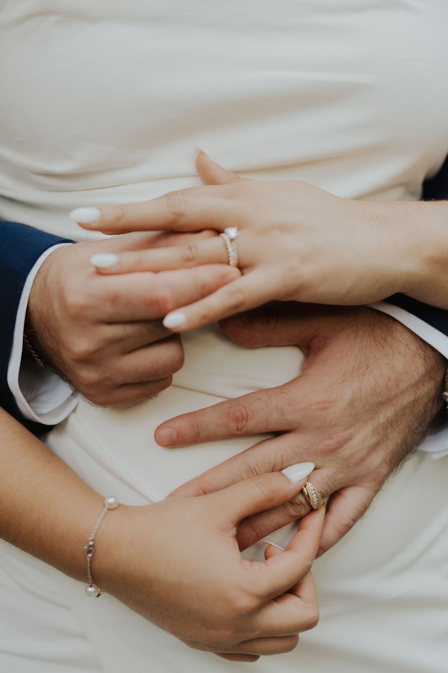 Close-up shot of hands exchanging wedding rings against a white background.