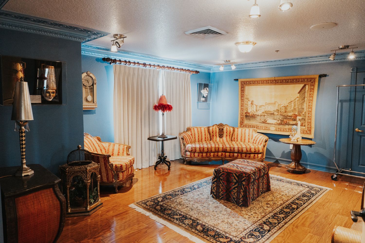 Blue-walled formal sitting room with ornate furniture, oriental rug, and classical artwork.