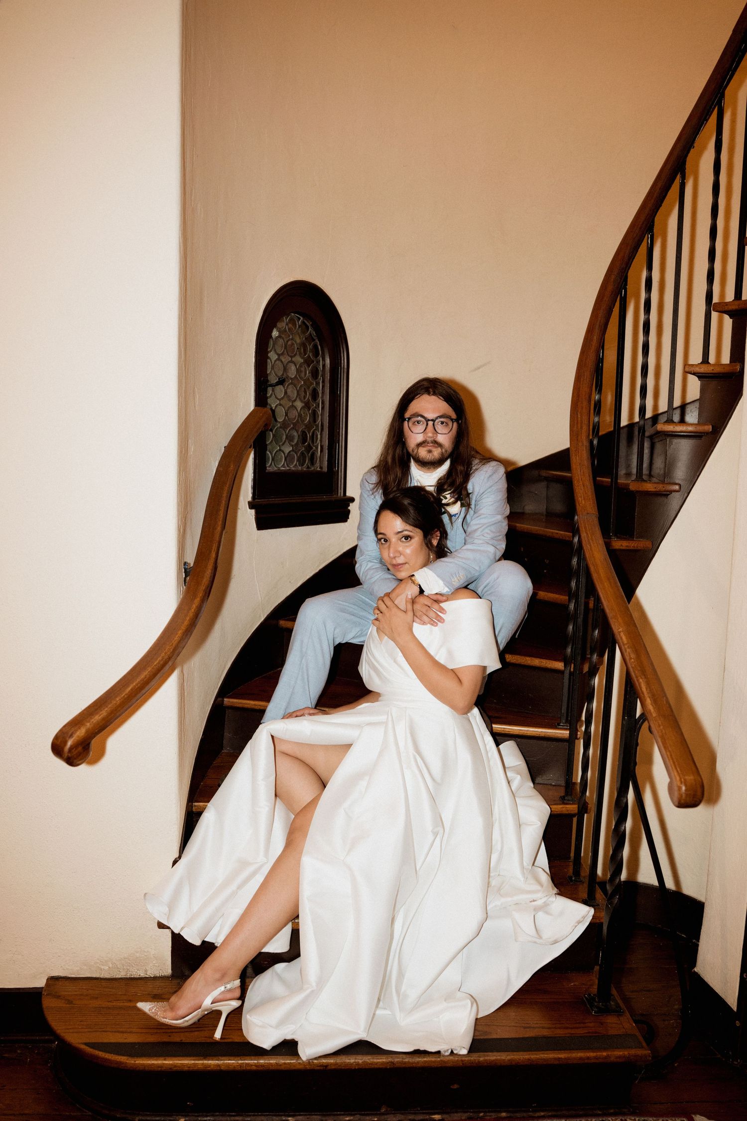 A series of playful staircase photos showing a couple in wedding attire posing on wooden steps.