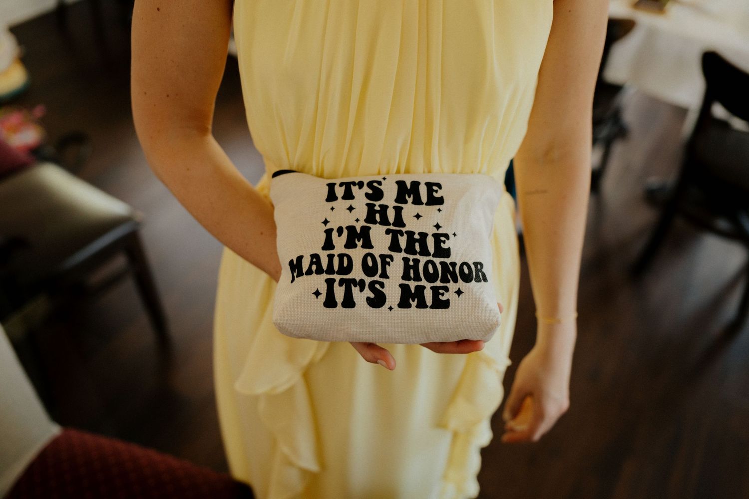 A pale yellow bridesmaid dress with text reading 'It's me I'm the maid of honor It's me' photographed in natural light.