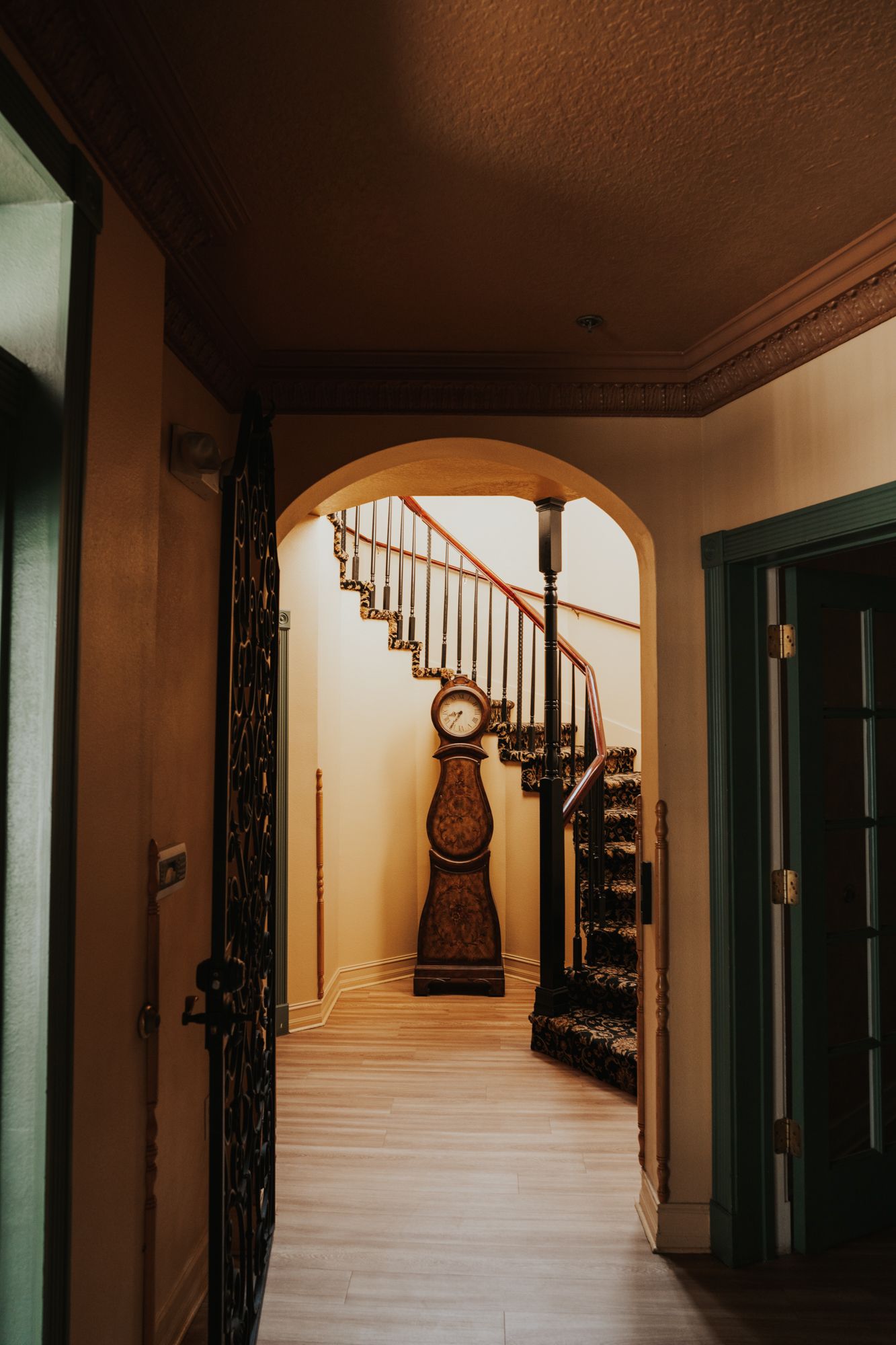 Curved staircase with antique grandfather clock visible through an archway.