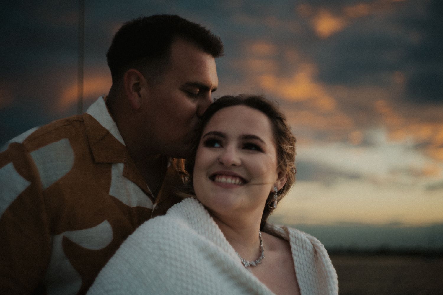 An intimate sunset moment between a couple with dramatic orange sky in the background.