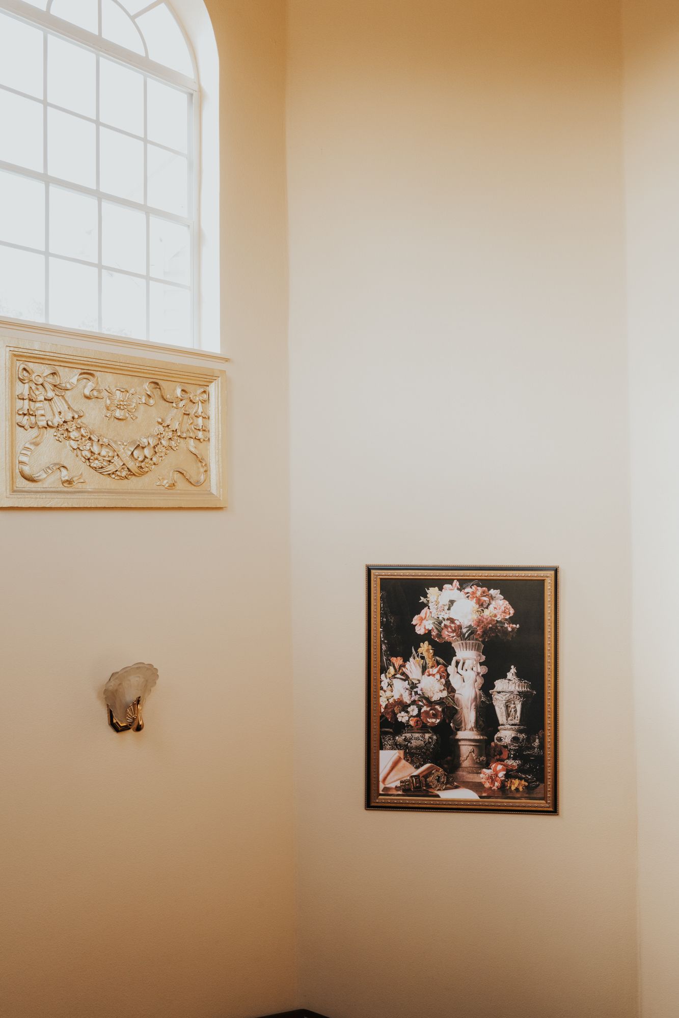 Decorative wall art and ornamental relief details beneath an arched window.