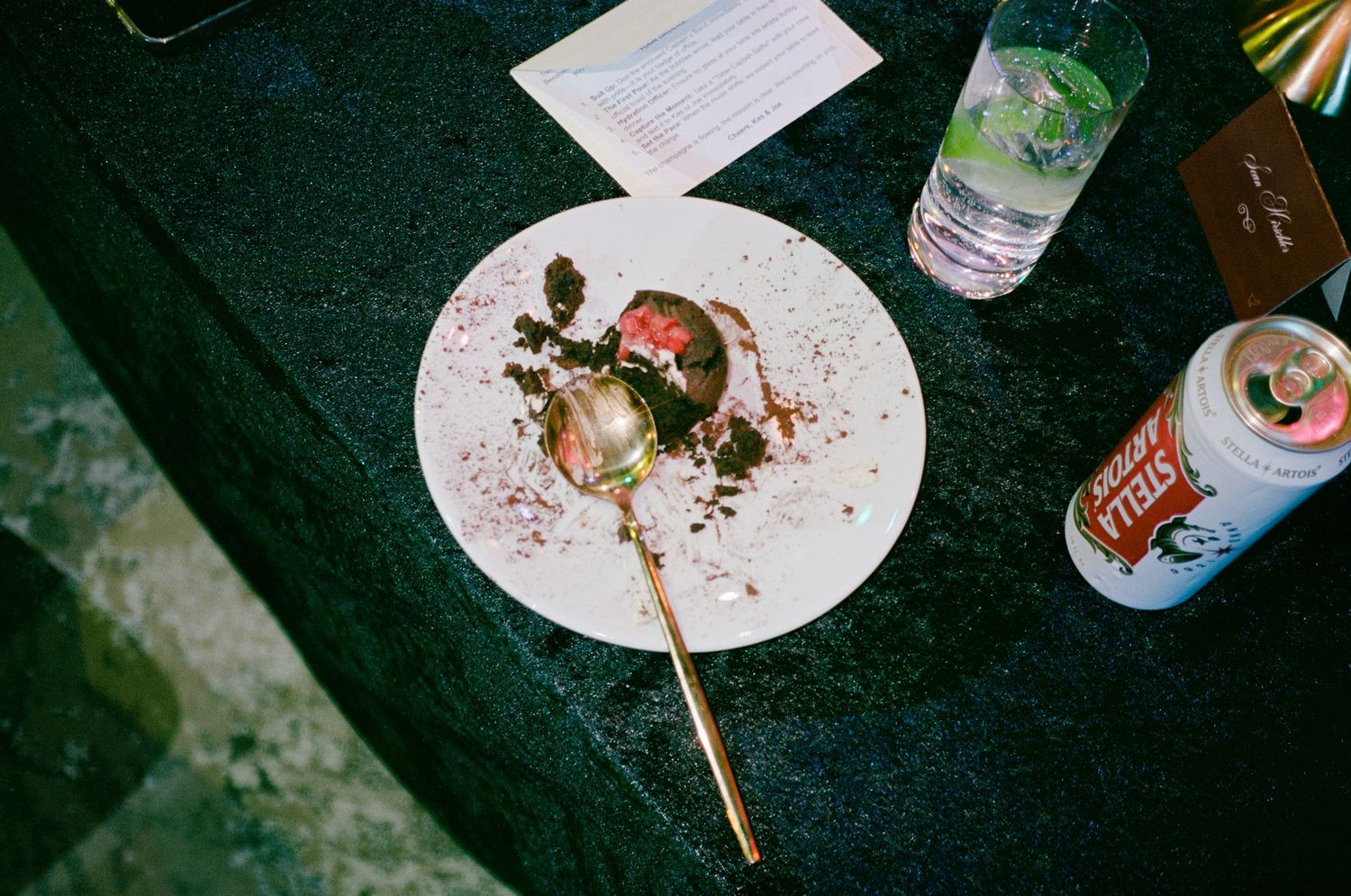 A photograph shot in film of Chocolate dessert on white plate with beer can at a wedding reception party.
