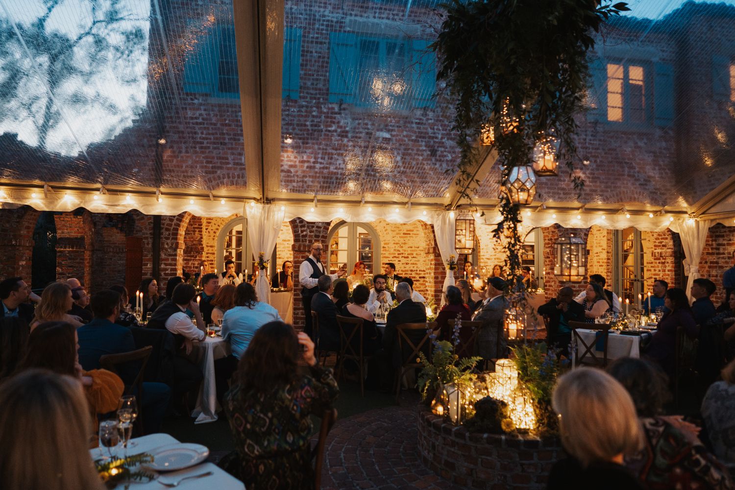 An atmospheric outdoor wedding reception with string lights and tables at dusk.