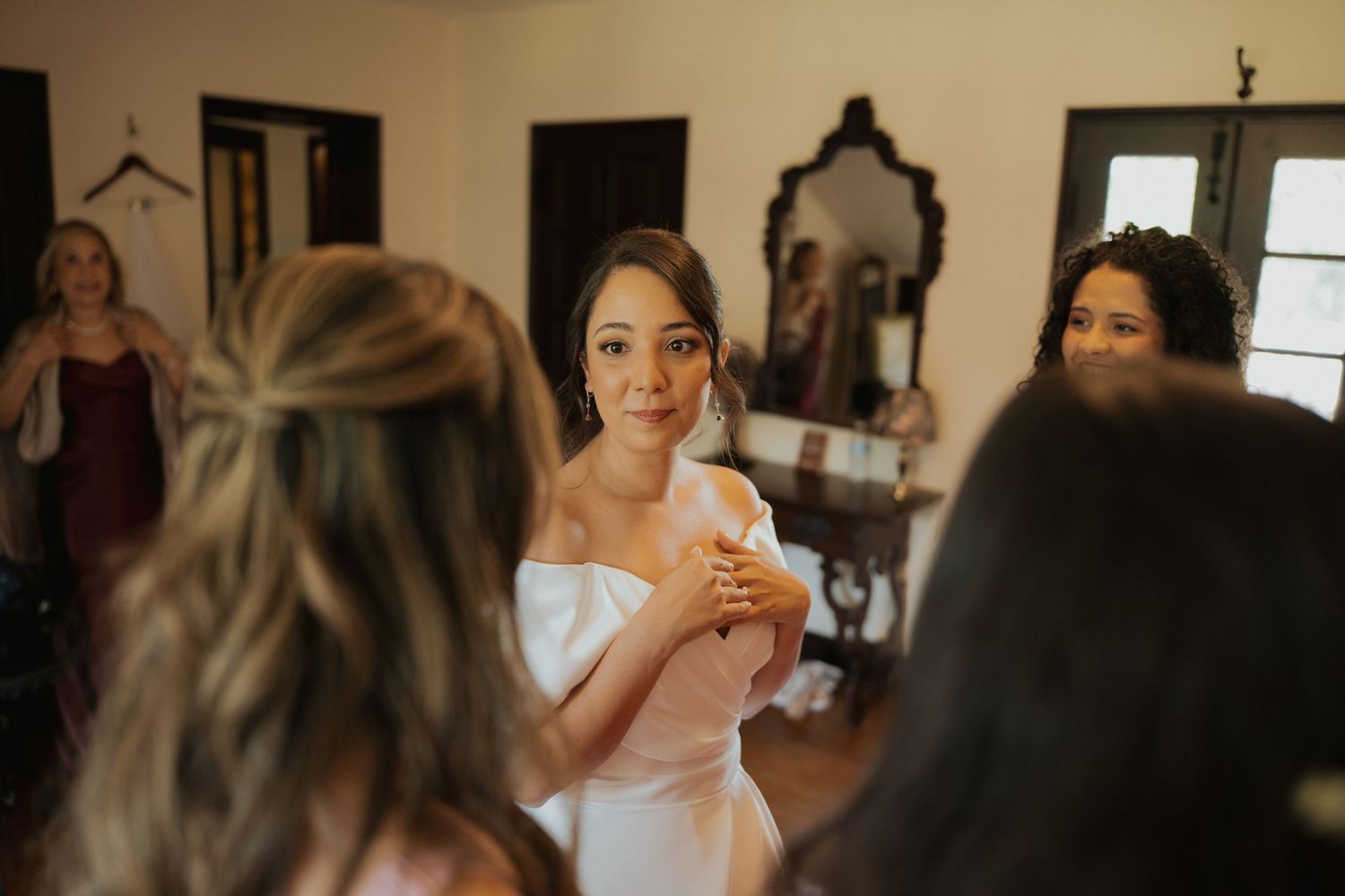 Wedding preparations in a rustic room with vintage mirror and elegant bridal attire.
