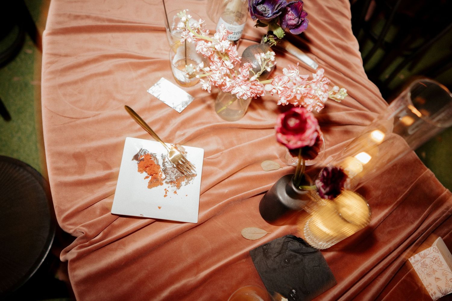 Wedding reception details showing pink tablecloth with flowers, candles and cards arranged on the table.