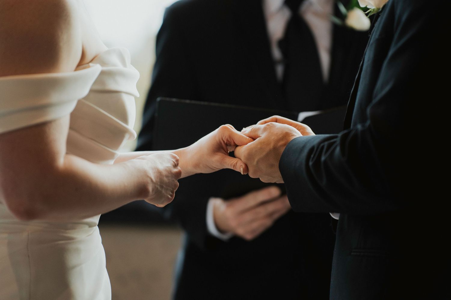 Close-up view of hands exchanging wedding rings during an elegant ceremony.