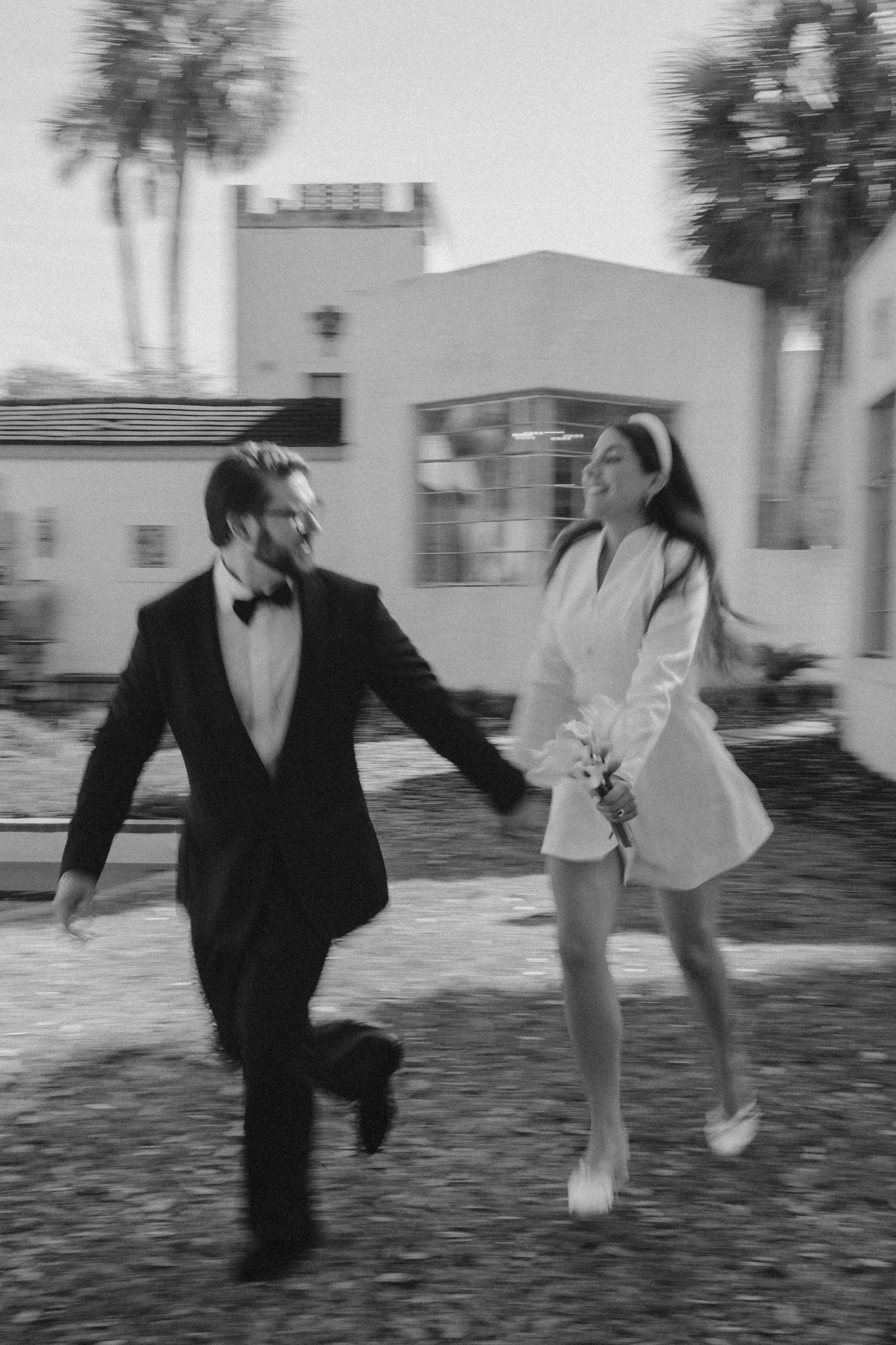 A sequence of black and white photos showing a couple playfully running and dancing together outdoors.