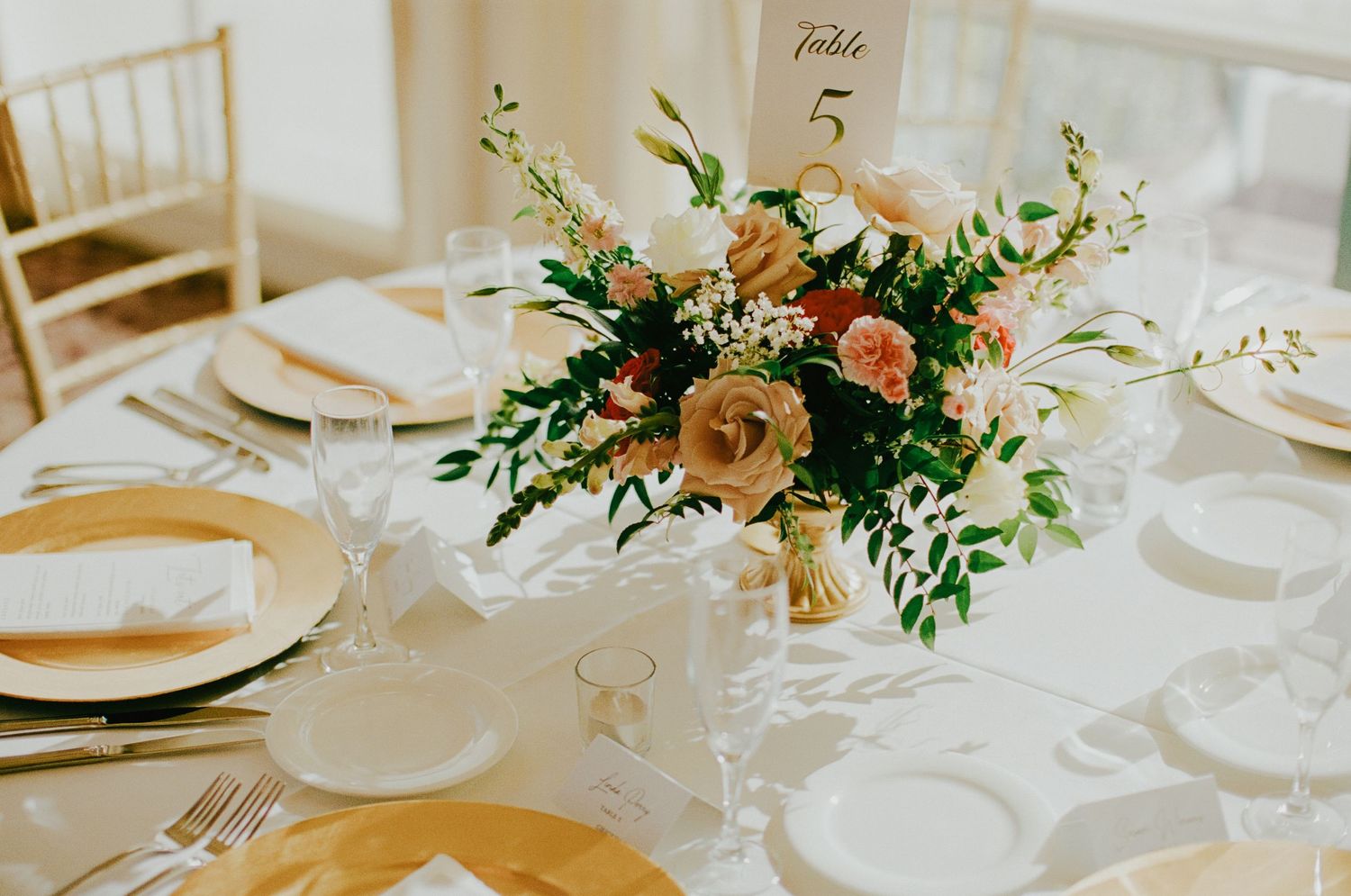 Elegant wedding reception table centerpiece with blush and peach flowers at Table 5 with gold accents.