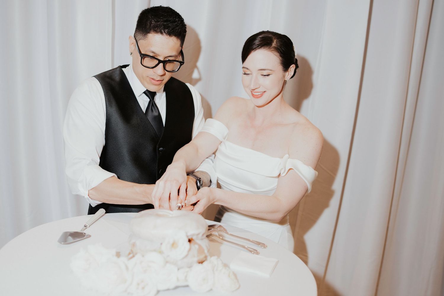Couple signs marriage documents at a table during an intimate wedding ceremony.