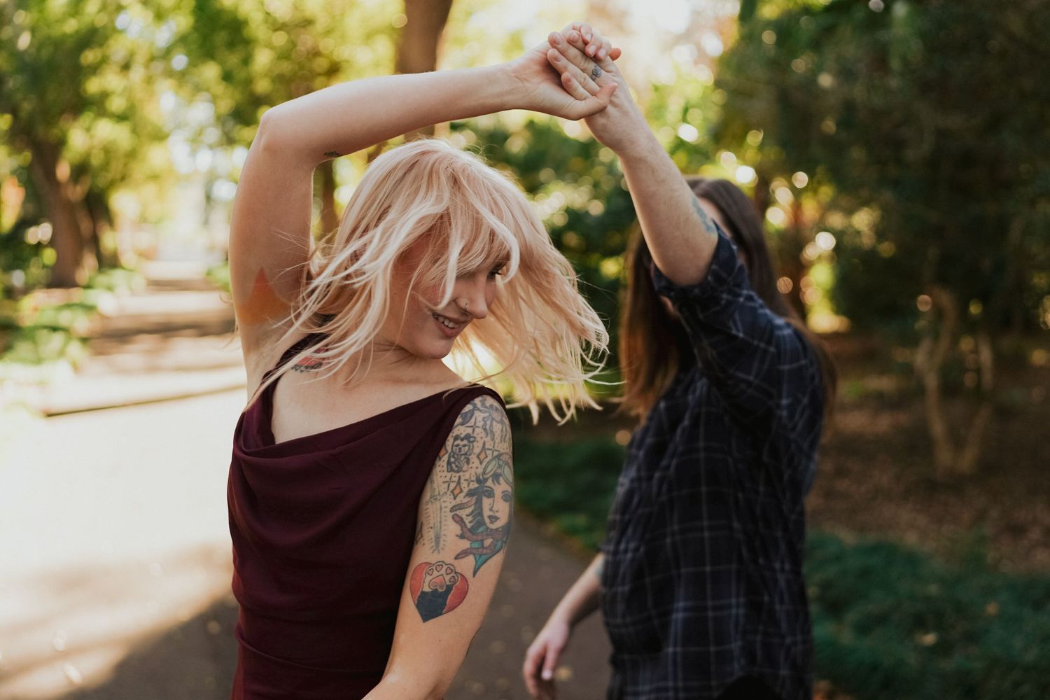 A couple dancing and twirling together on a sunny forest path.