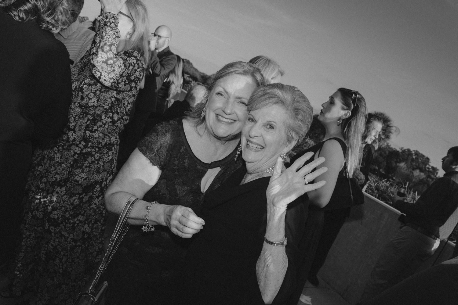 A series of black and white candid photos showing people laughing and enjoying themselves at an outdoor gathering.