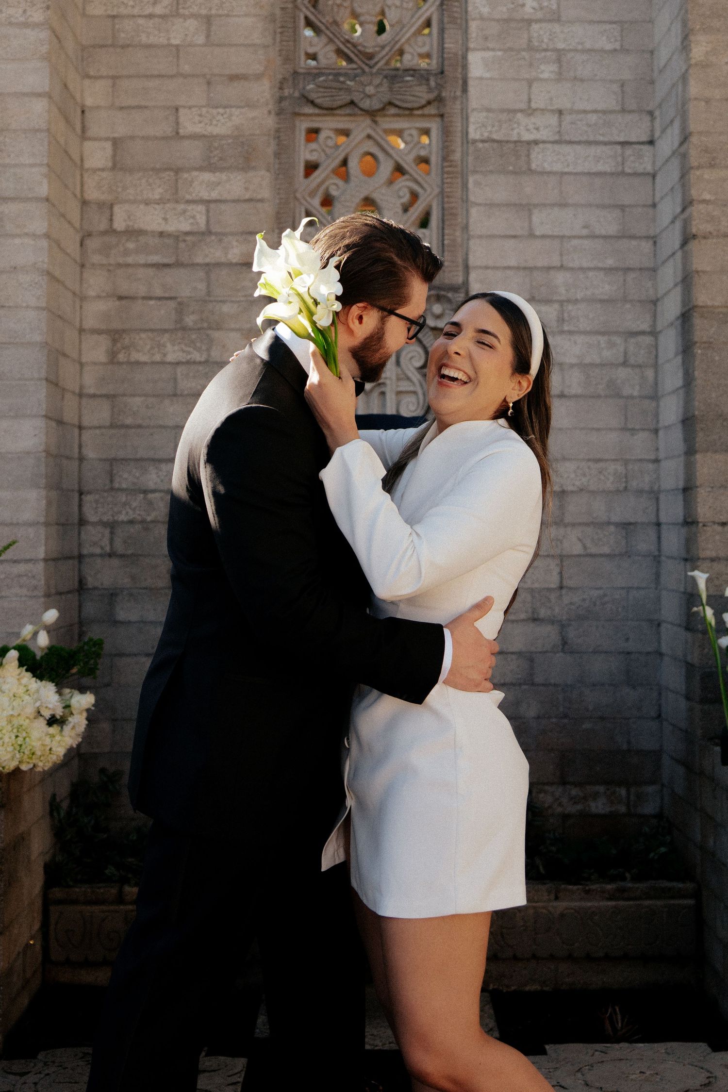 Couple sharing an intimate moment against a stone wall backdrop during their wedding celebration.