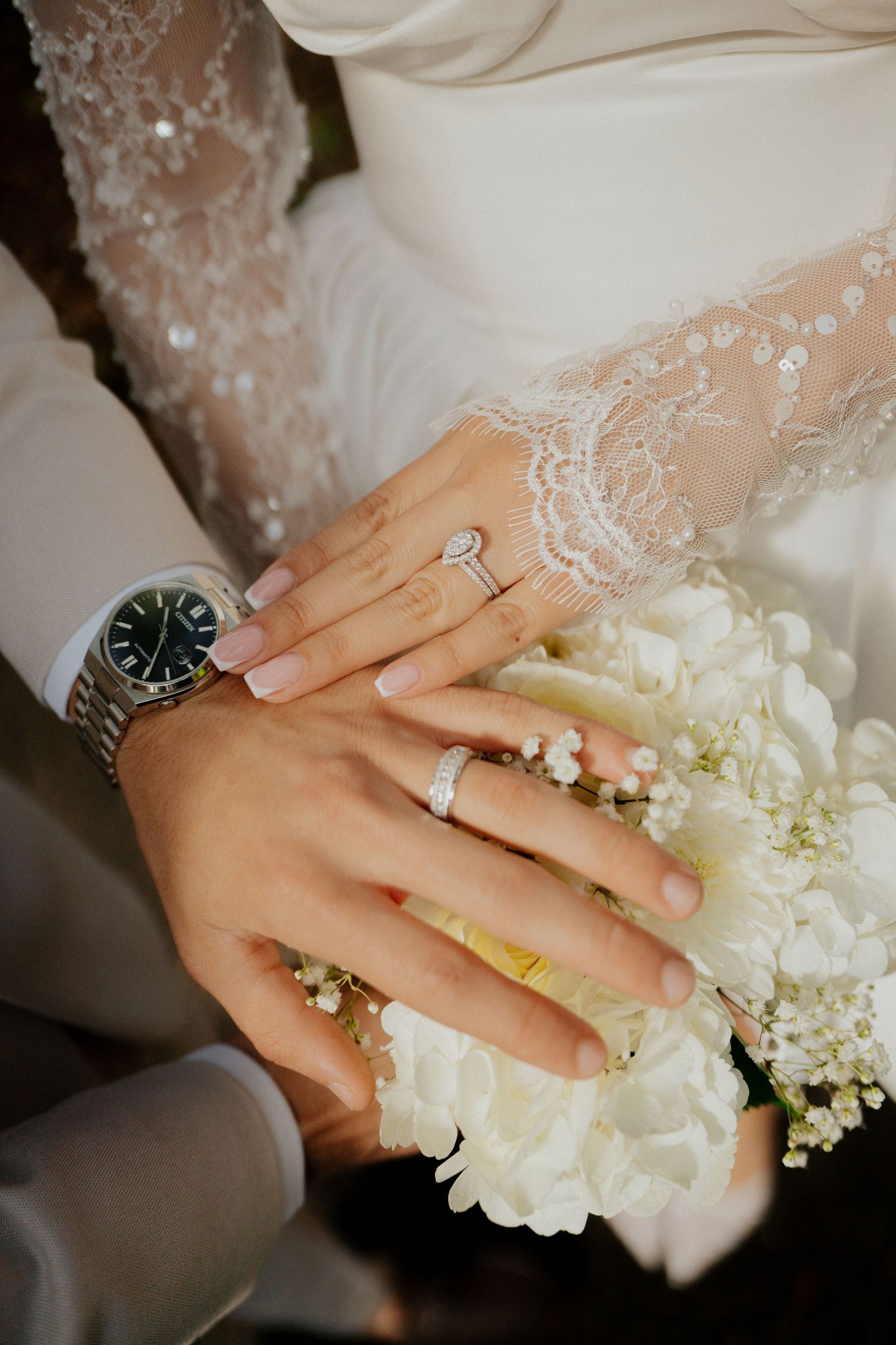 Close-up sequence of hands wearing wedding rings and holding white flowers with delicate lace details.