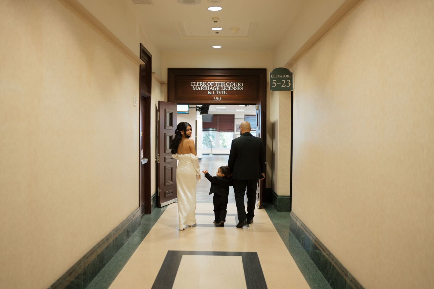 A couple walking down a hotel hallway together after their wedding ceremony.