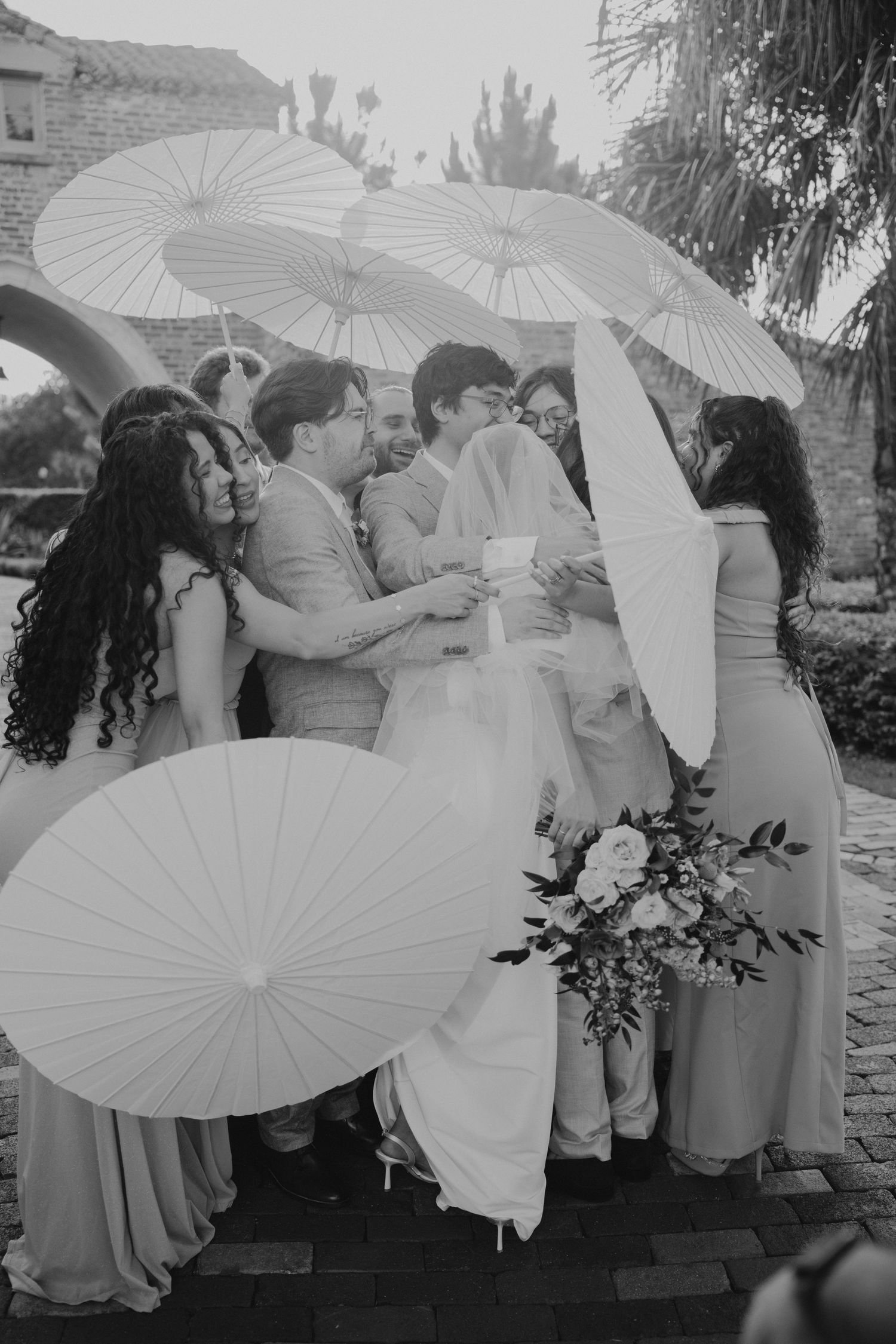 Wedding party posing with white parasols in black and white photography style outside casa feliz.