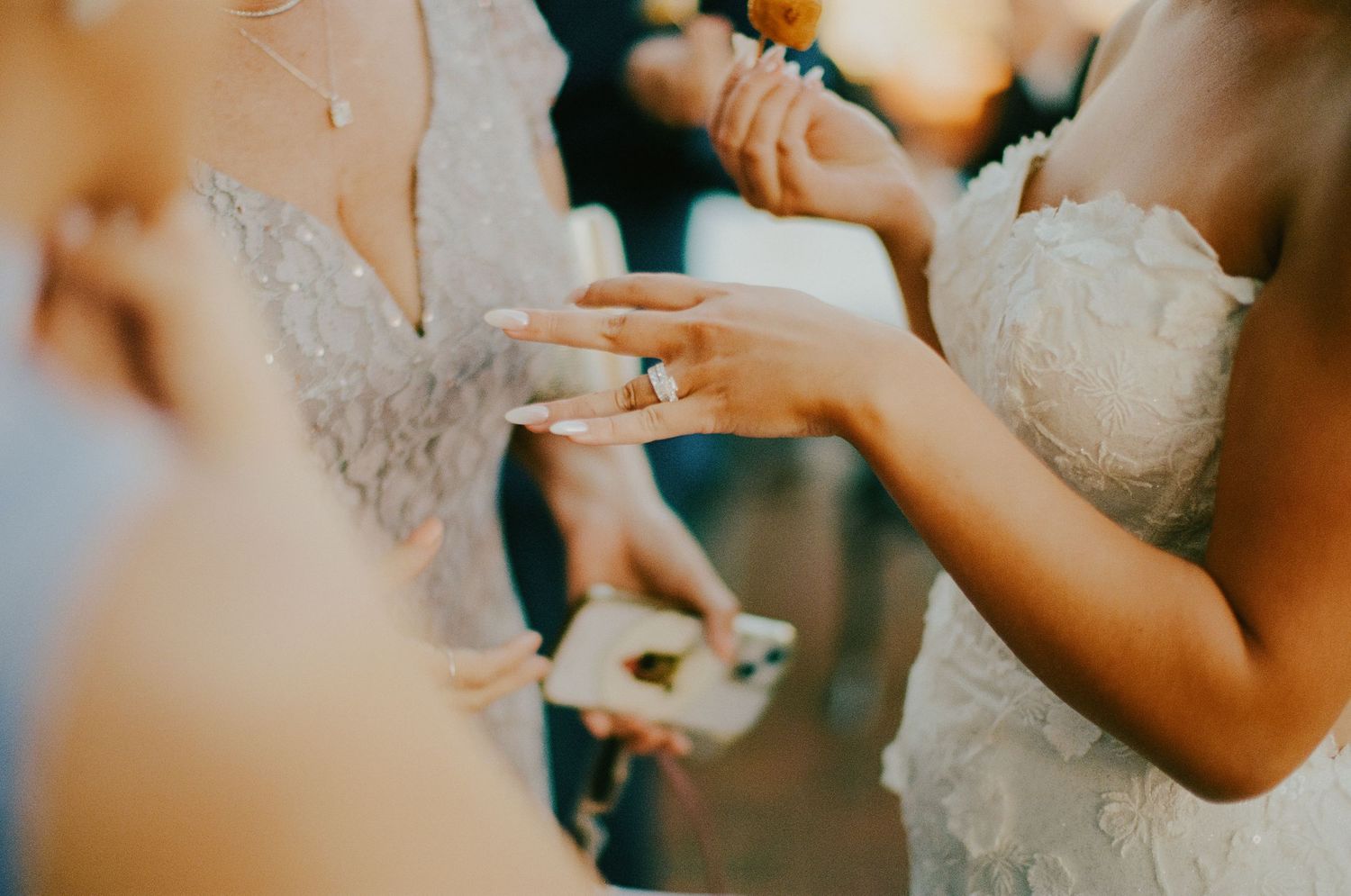 Close-up of bride admiring her diamond wedding ring while wearing a lace wedding dress at the ceremony.