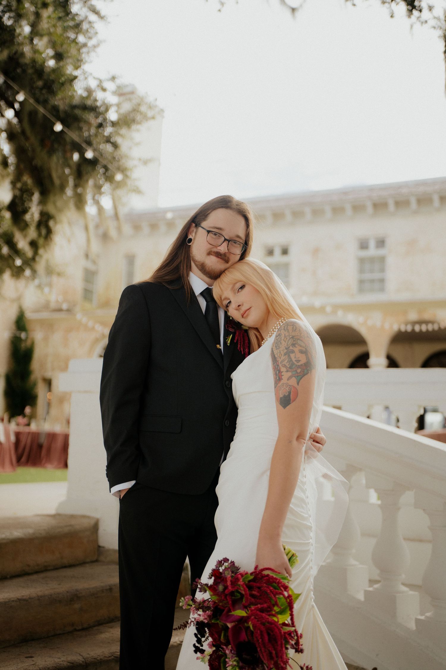 A romantic wedding couple shares a candid moment together on a sunlit terrace with white balustrades.