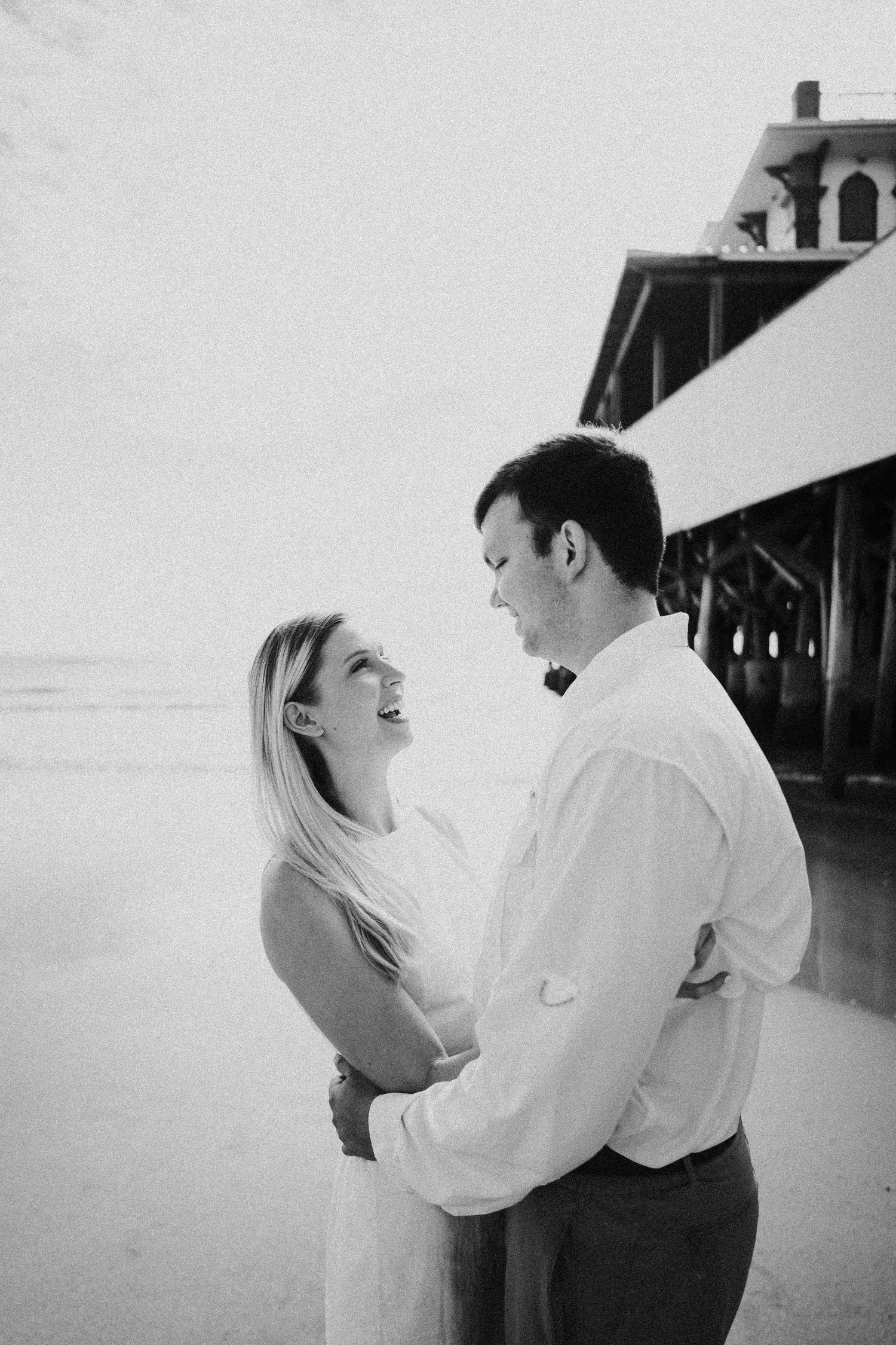 A romantic seaside moment captured in black and white by a vintage pier.