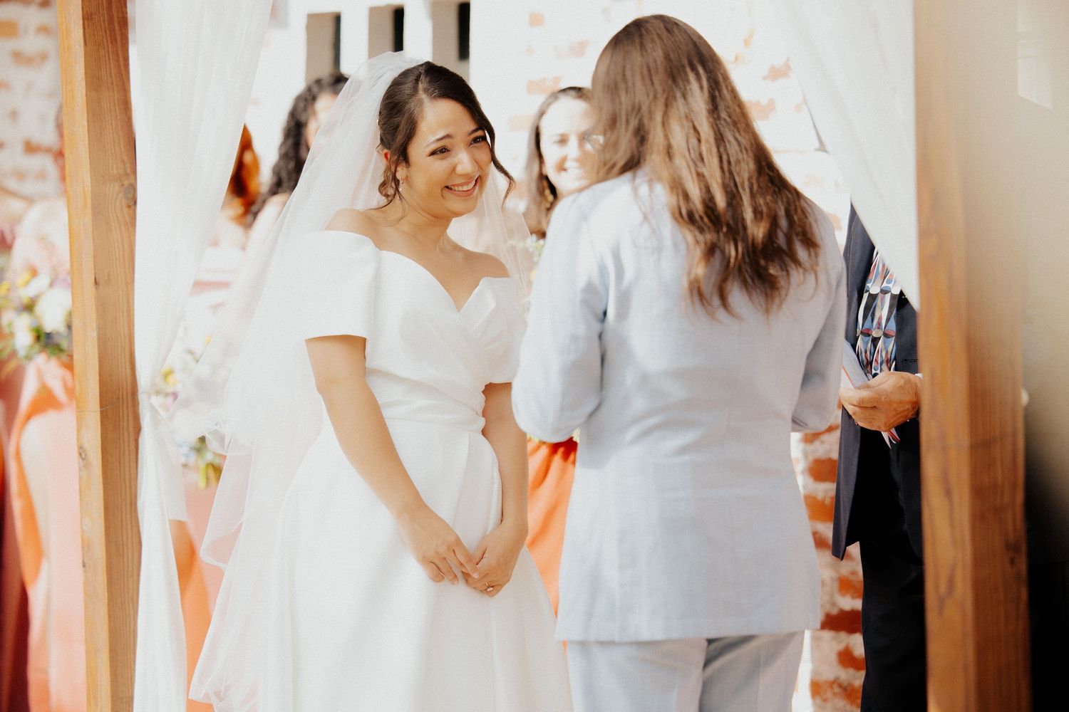 White fabric and floral decorations adorn a rustic brick wall at an outdoor wedding venue.