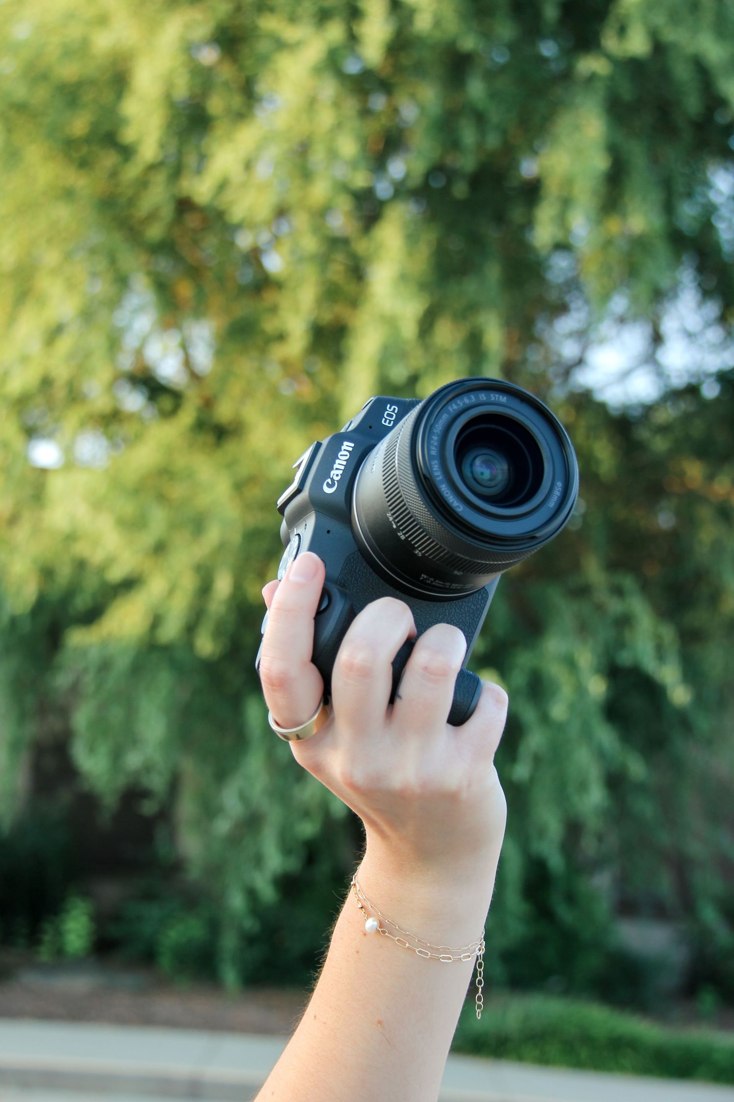 Photographer holding camera outdoors surrounded by greenery.