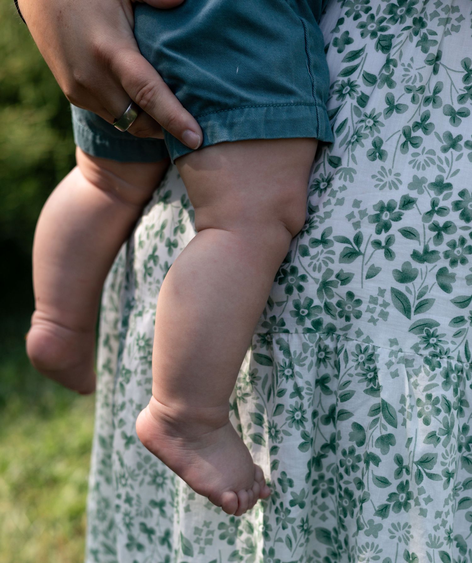 Close-up of a mother holding her young child's bare feet during an outdoor family session.