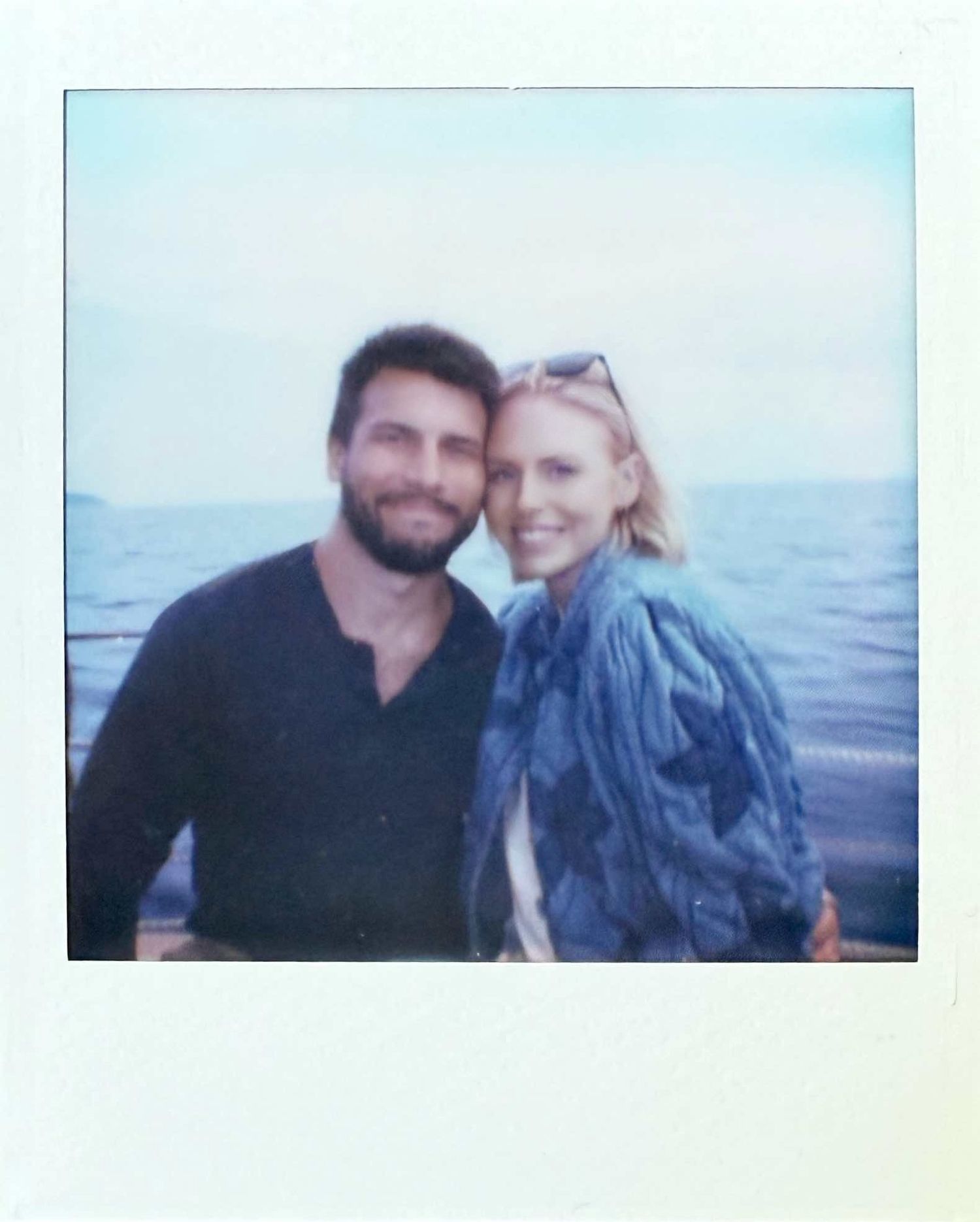 Happy couple smiling together on a boat with calm ocean backdrop, Polaroid photo.