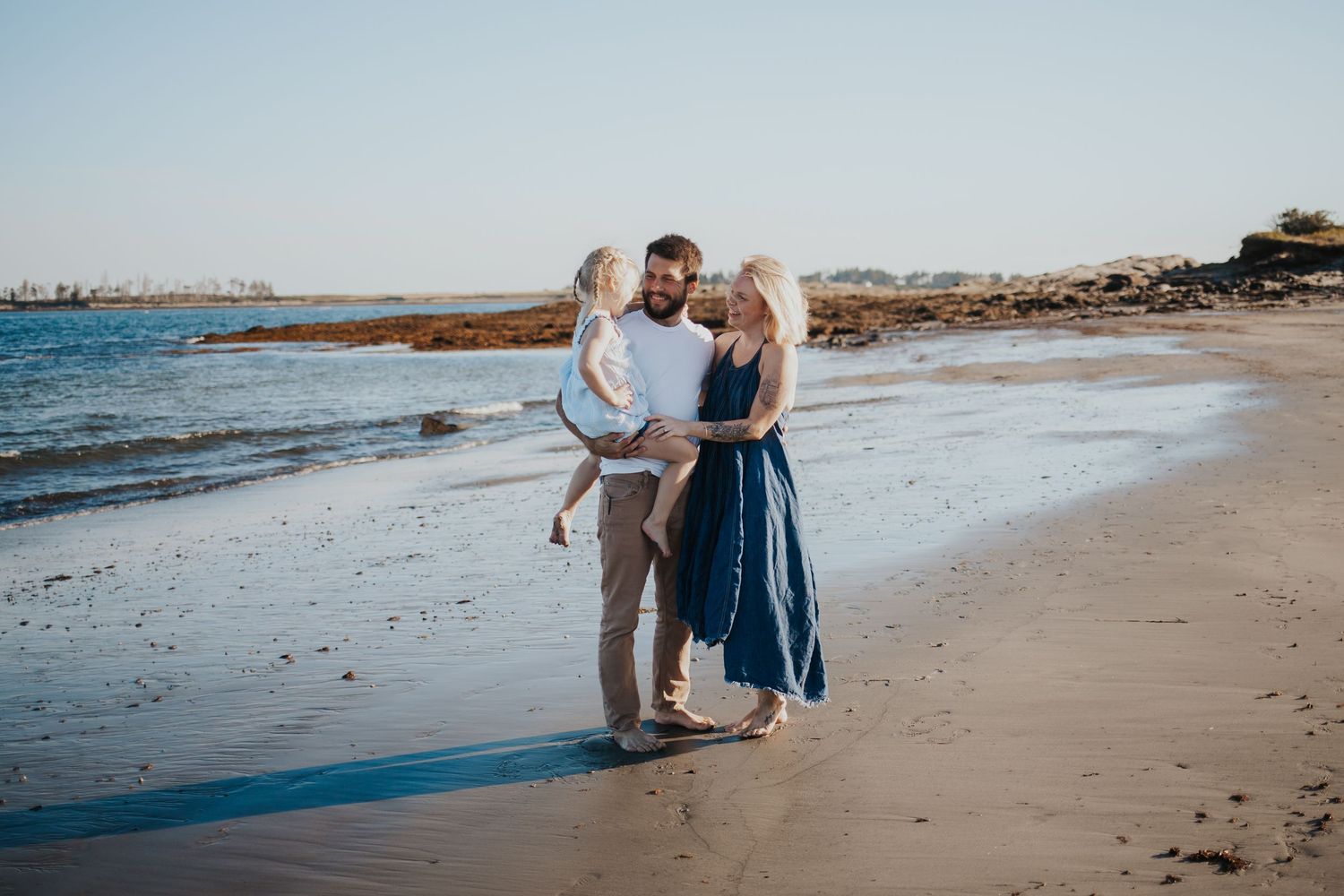 Happy family with young child sharing a tender moment on a sunny beach.
