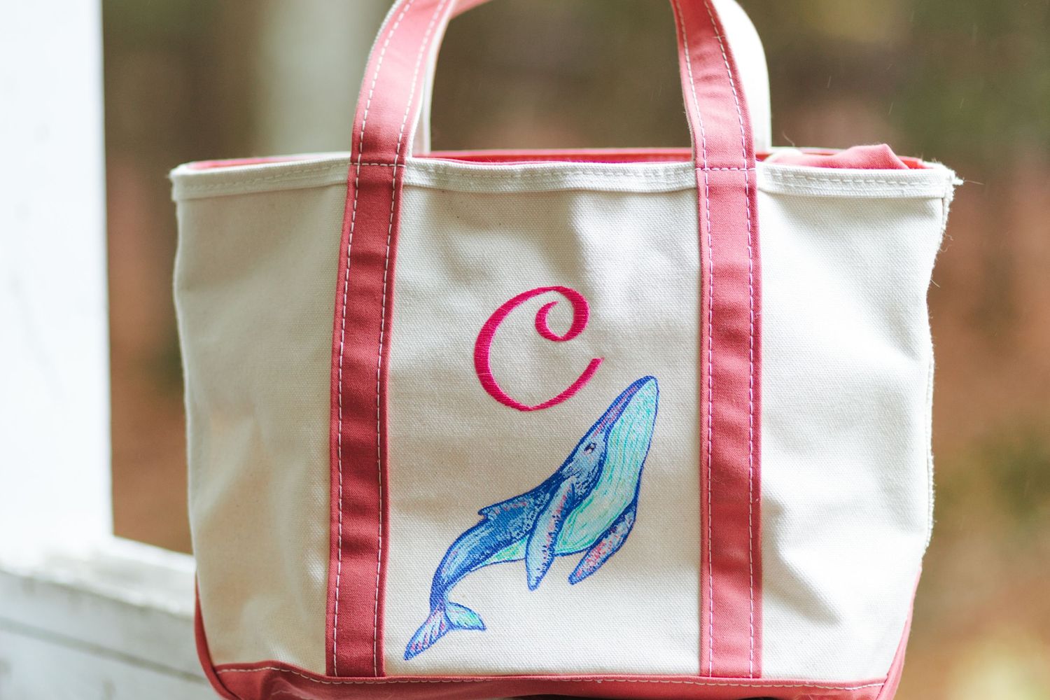Canvas tote bag with pink trim, monogram letter C, and embroidered blue whale design.