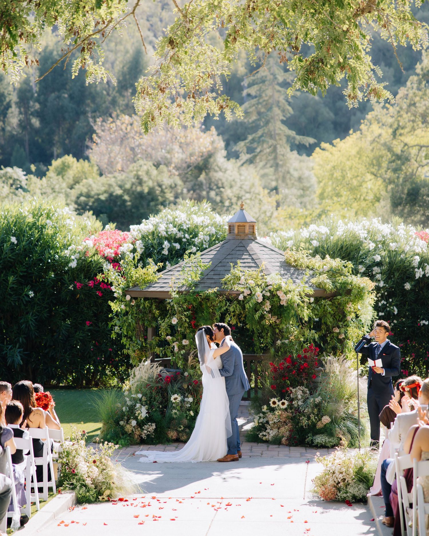 Bride and groom share first kiss at outdoor garden wedding ceremony at Elliston Vineyards in Sunol, California.