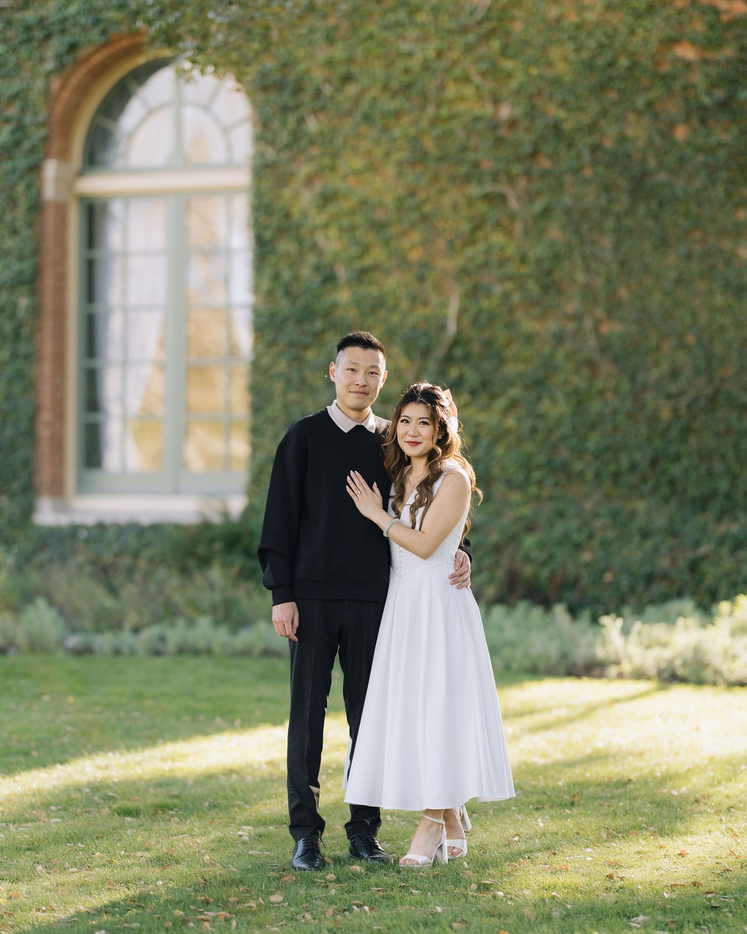 Couple posing in front of an ivy-covered building during a garden engagement session at Filoli Woodside CA.