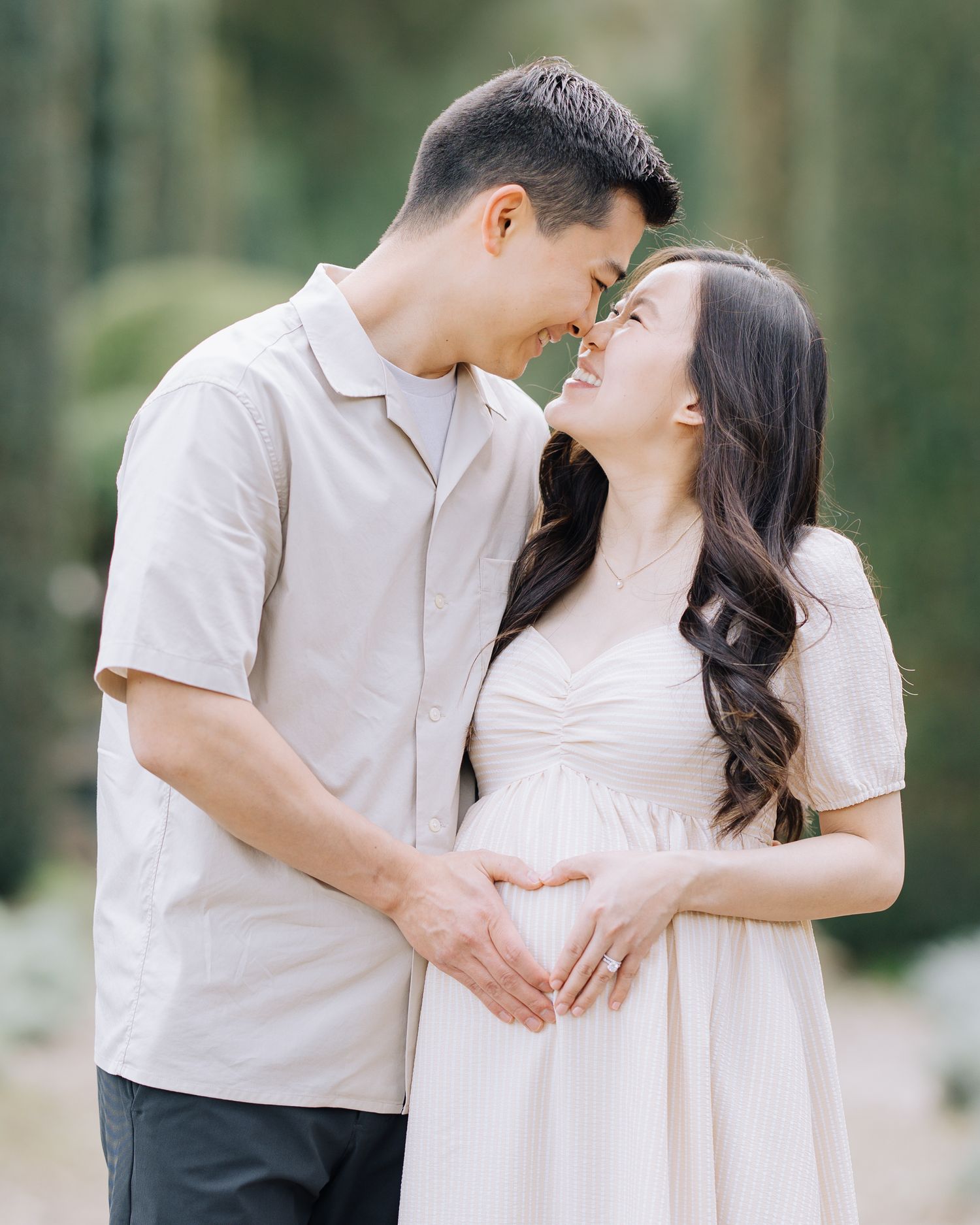Asian couple sharing a tender moment during maternity photoshoot, forming heart shape over baby bump at Filoli Woodside CA.