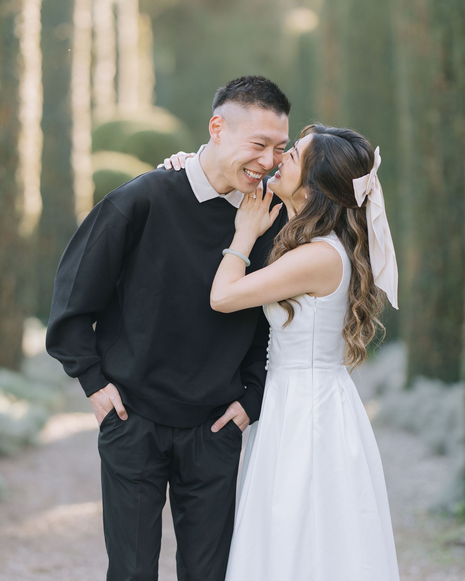 Laughing couple sharing a playful moment together on a sunlit tree-lined garden path during Filoli engagement photoshoot.