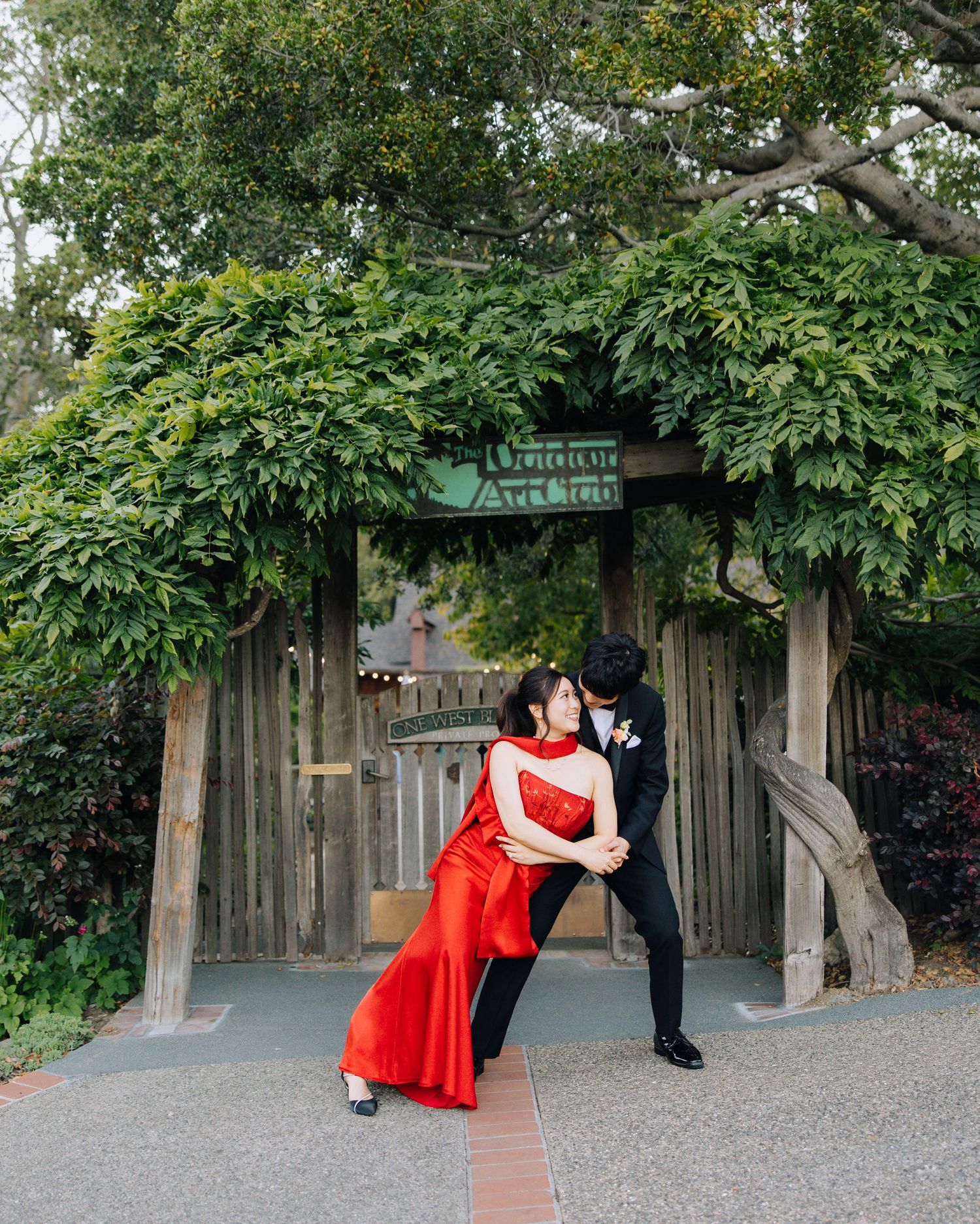 Couple sharing a romantic dip kiss in front of a vine-covered wooden arbor during wedding at Outdoor Art Club in Mill Valley, CA.