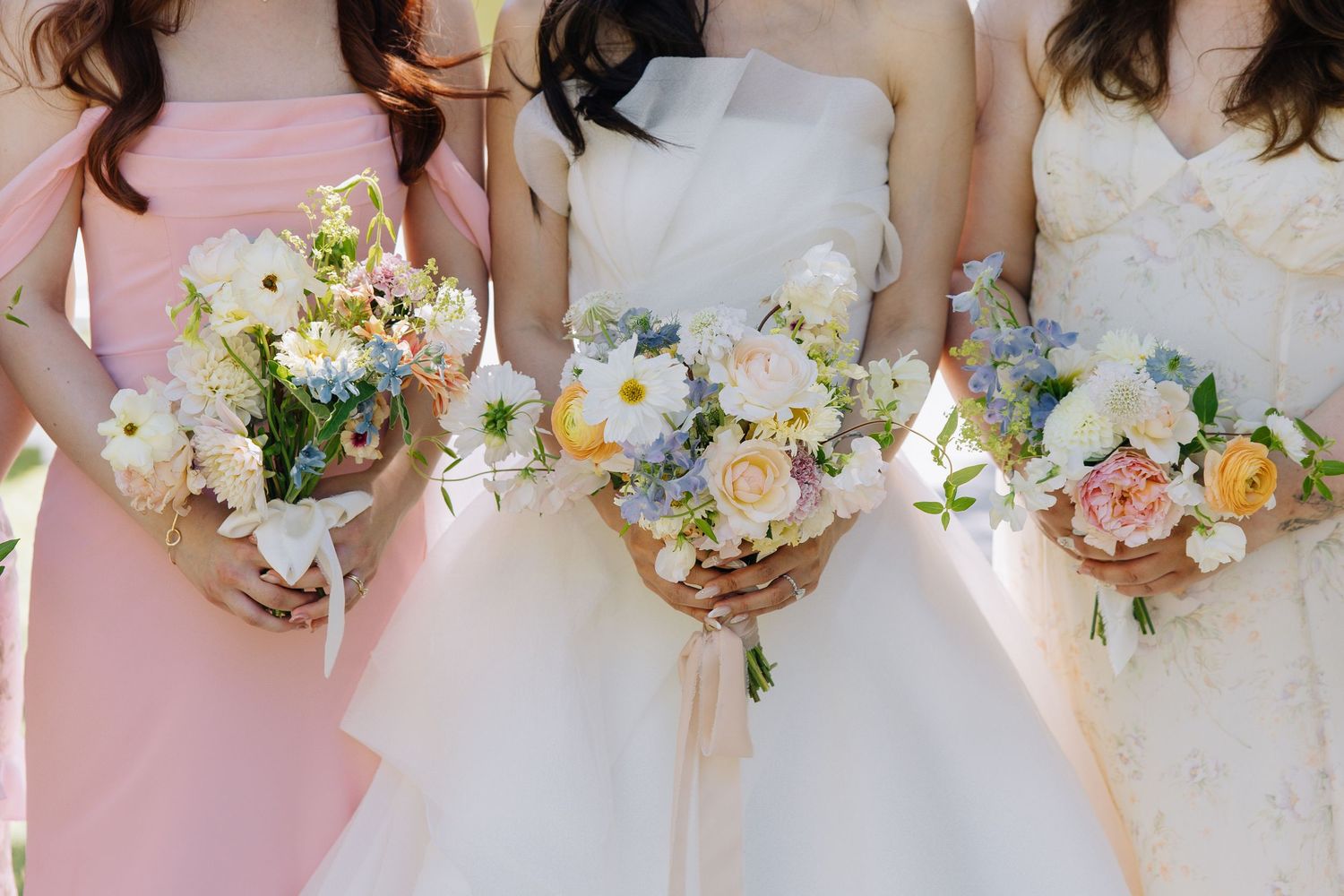 Bride and two bridesmaids in pink dresses hold colorful spring wedding bouquets at Elliston Vineyards in Sunol, California.